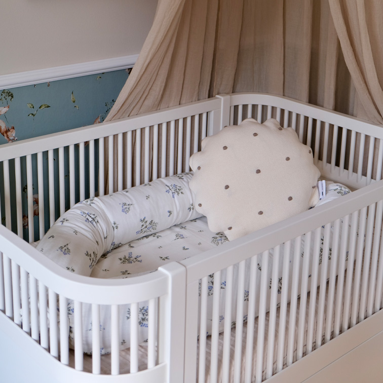 Lettino bianco per bambini con cuscino morbido e biancheria da letto floreale in tonalità pastello