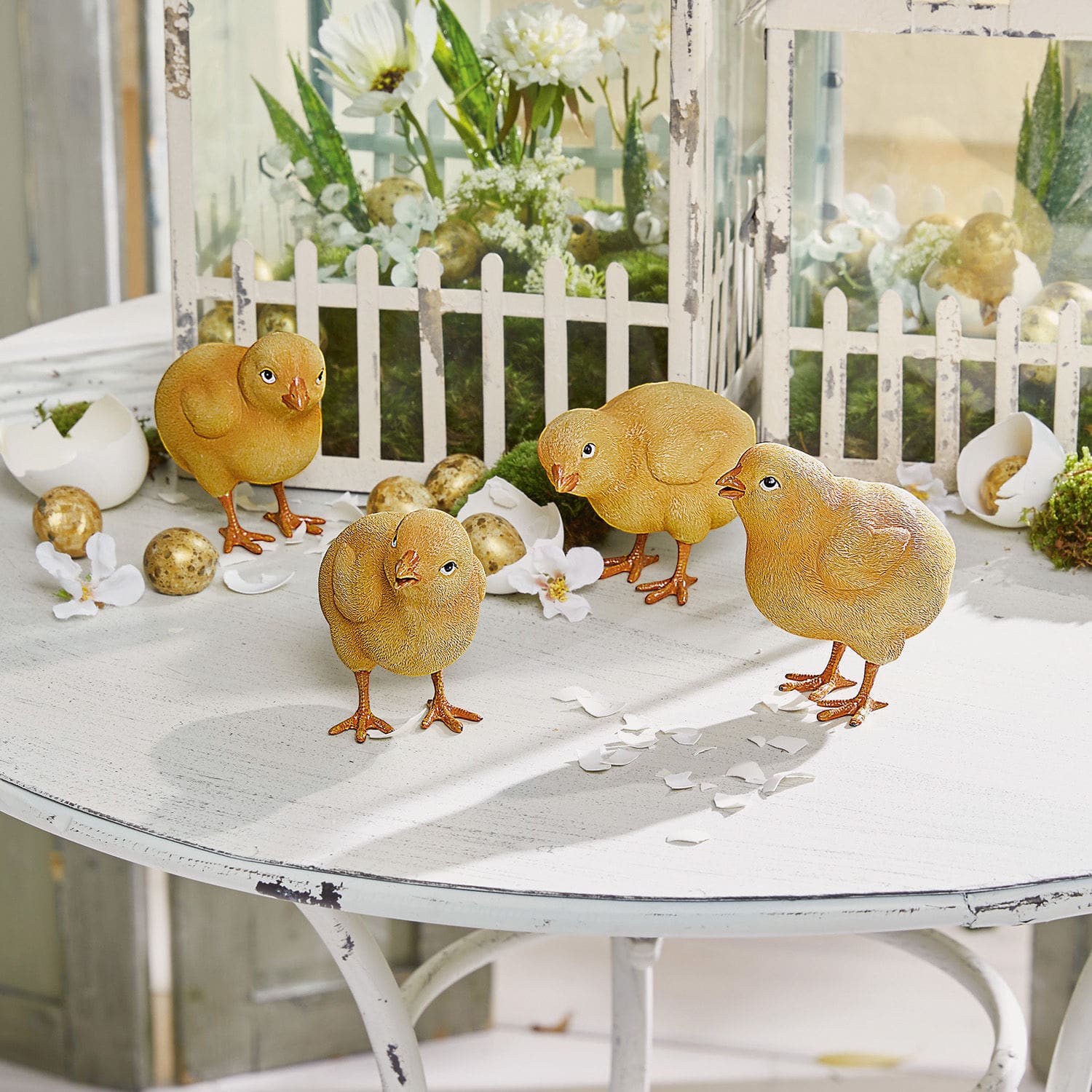 Set di 4 pulcini Wendolin Quattro pulcini decorativi gialli su tavolo bianco con decorazioni pasquali e uova finte