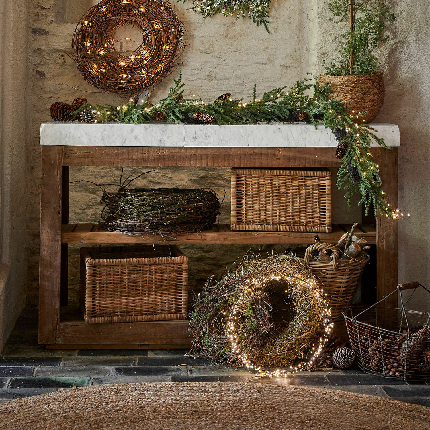 Tavolo rustico in legno con piano in marmo e decorazioni natalizie con rami e luci LED