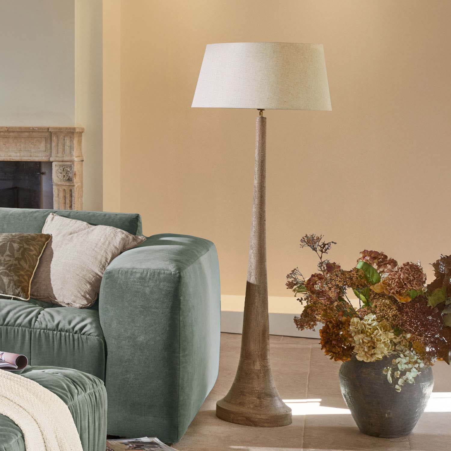 Lampada da terra con base in legno e paralume beige in soggiorno moderno con divano verde