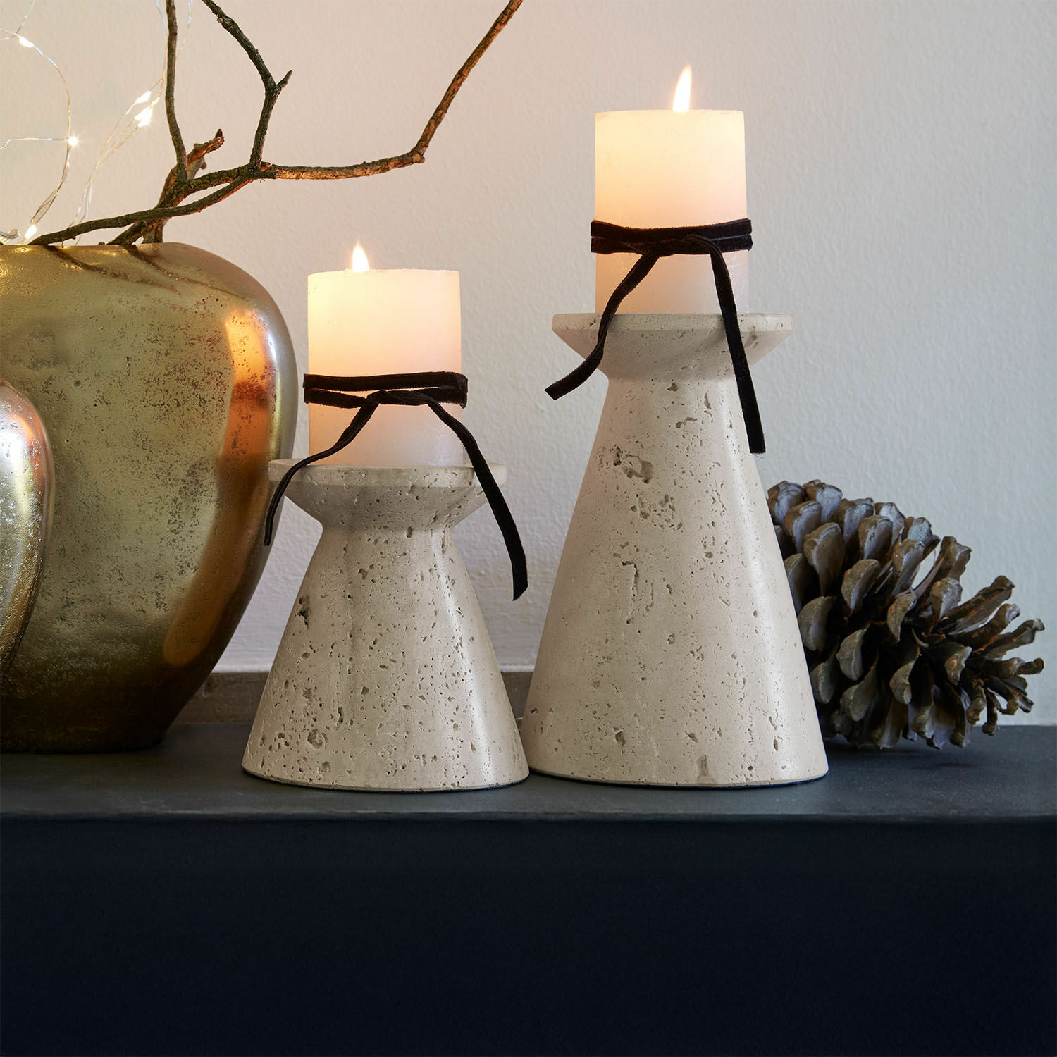 Coppia di candelieri Bazrahim Due portacandele in cemento beige con candele bianche e nastri neri su tavolo decorativo