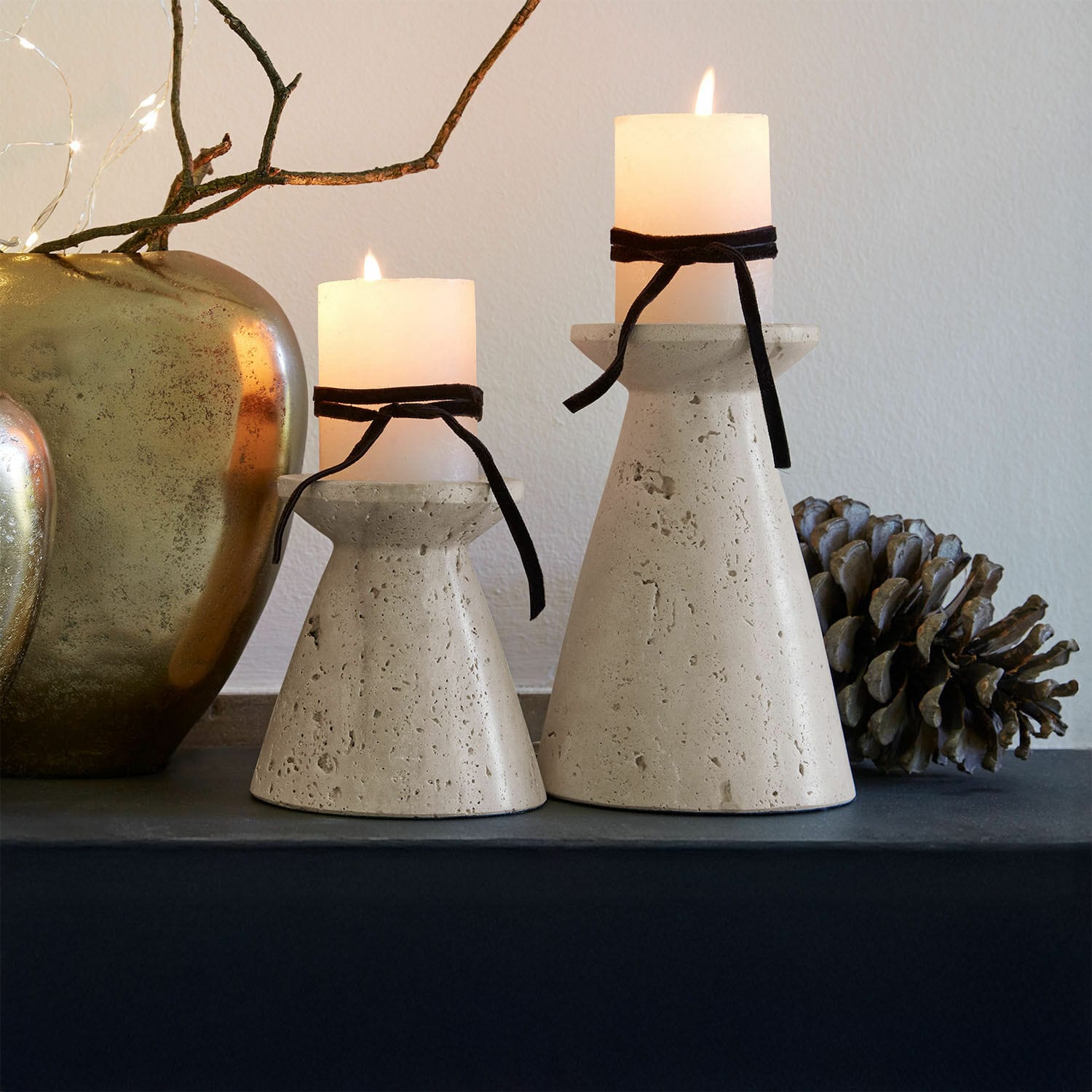 Coppia di candelieri Bazrahim Due portacandele in cemento beige con candele bianche e nastri neri su tavolo decorativo