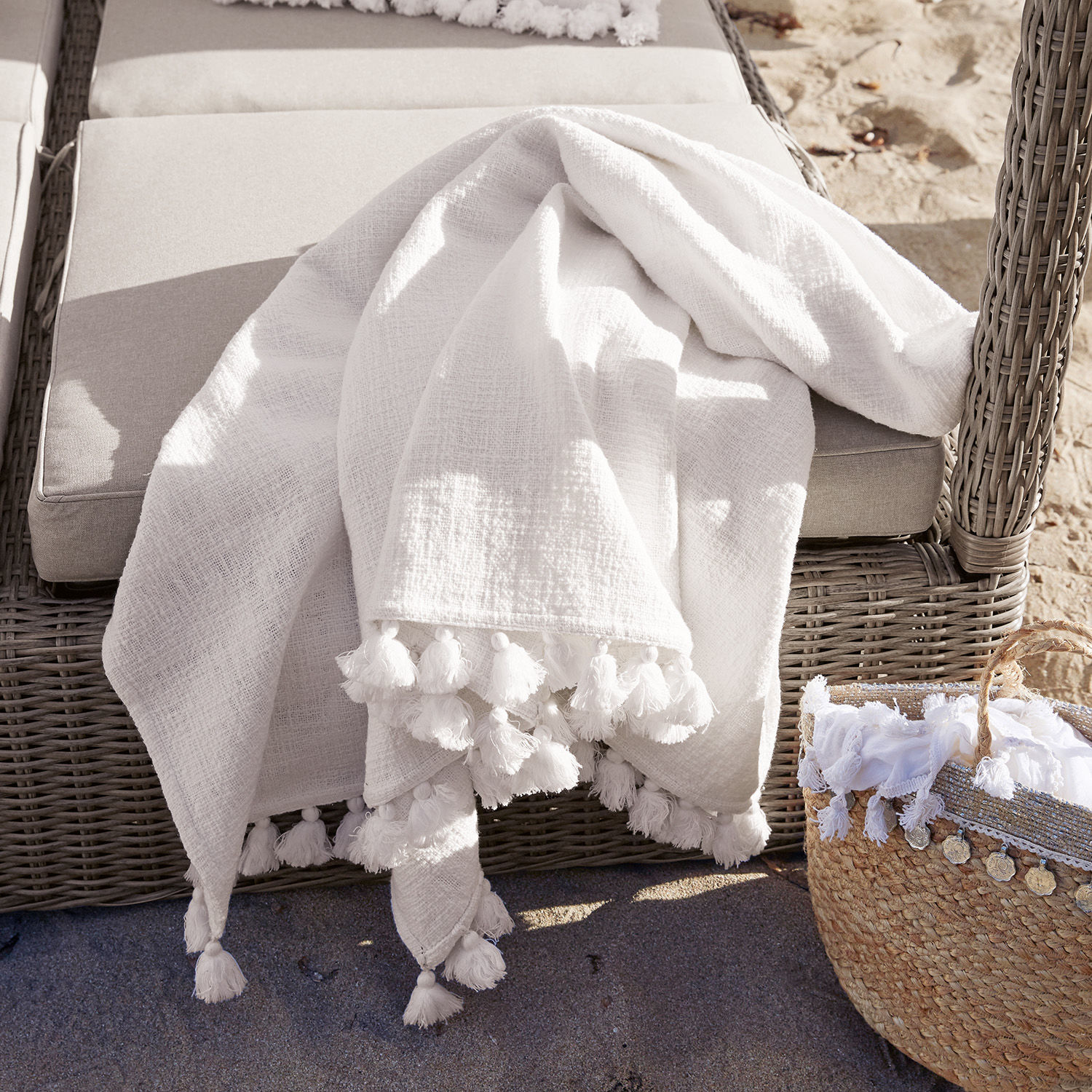 Coperta Amlamé Coperta bianca in cotone con nappine su poltrona in rattan grigio, decorazione da giardino esterno