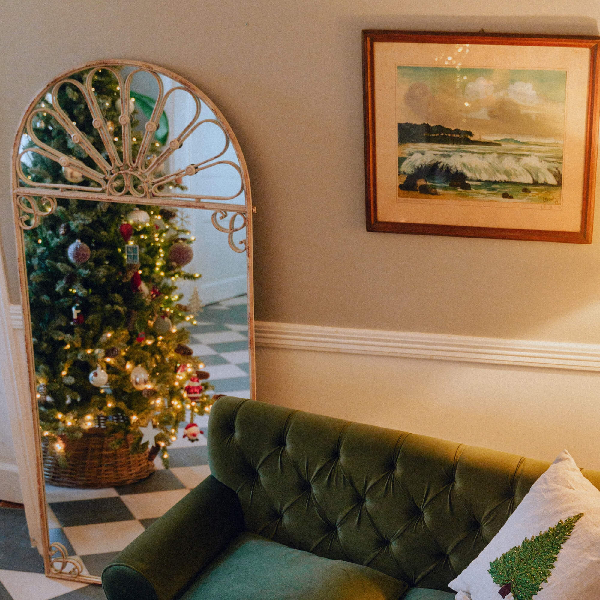 Specchio decorativo vintage in metallo che riflette l'albero di Natale e il divano verde nel soggiorno