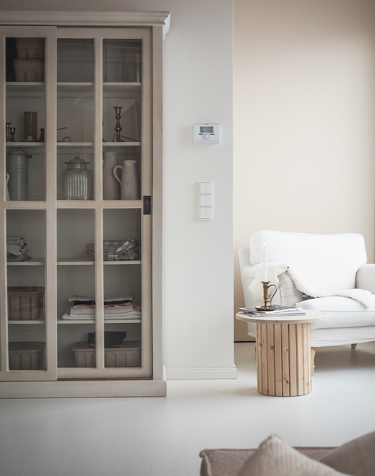 Soggiorno luminoso con divano bianco, tavolino in legno e vetrina in stile scandinavo