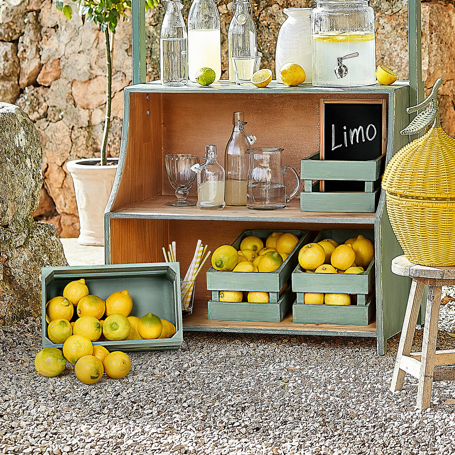 Coppia di cesti Éclairon Scaffale in legno verde con limoni e bottiglie di vetro per limonata all'aperto