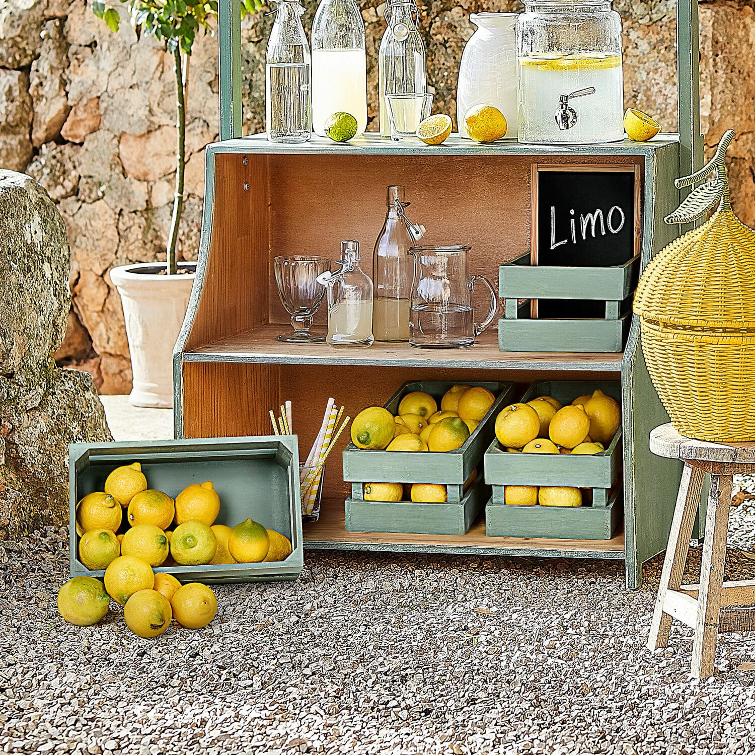 Coppia di cesti Éclairon Scaffale in legno verde con limoni e bottiglie di vetro per limonata all'aperto