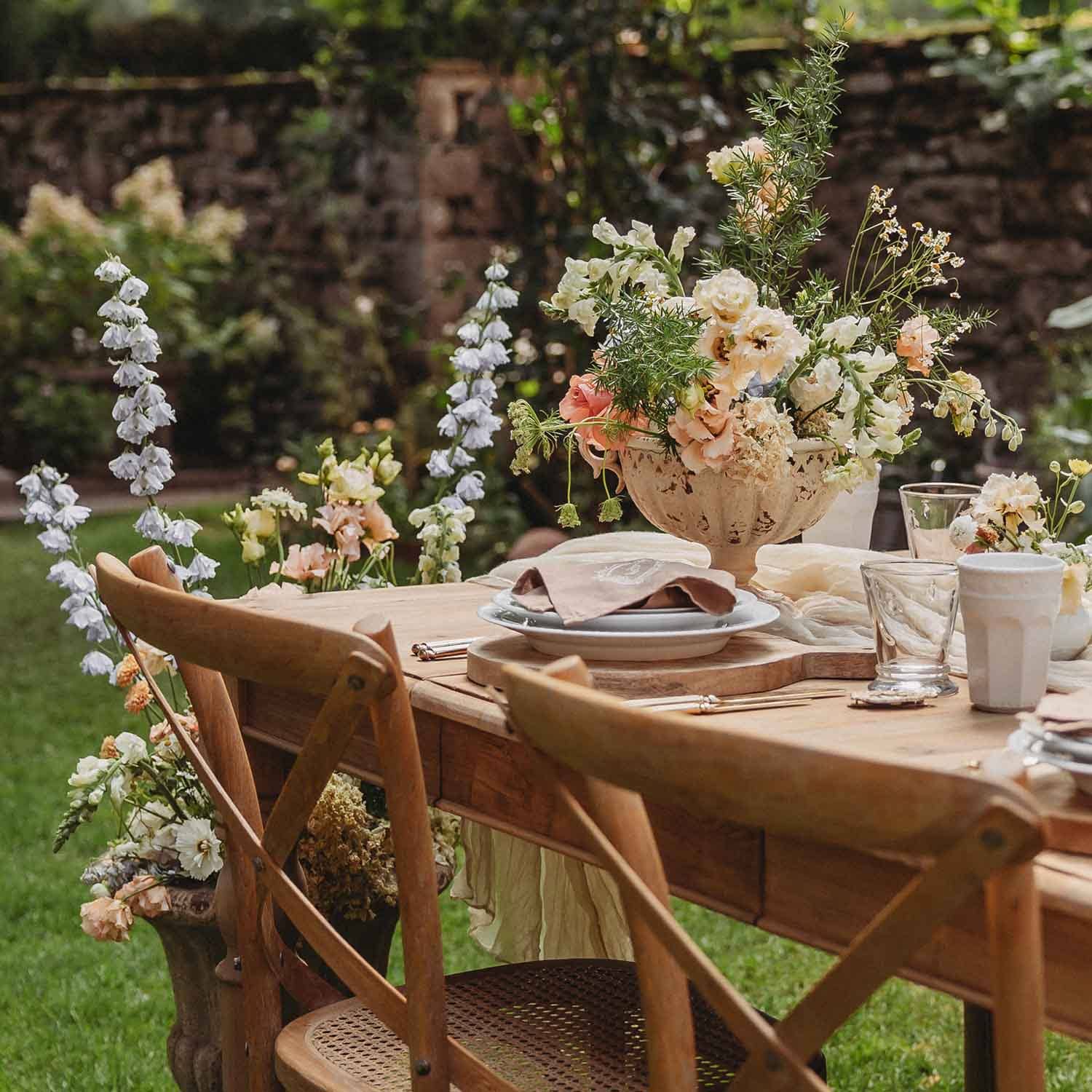 Tavolo da giardino in legno con sedie rustiche e decorazione floreale in tonalità pastello