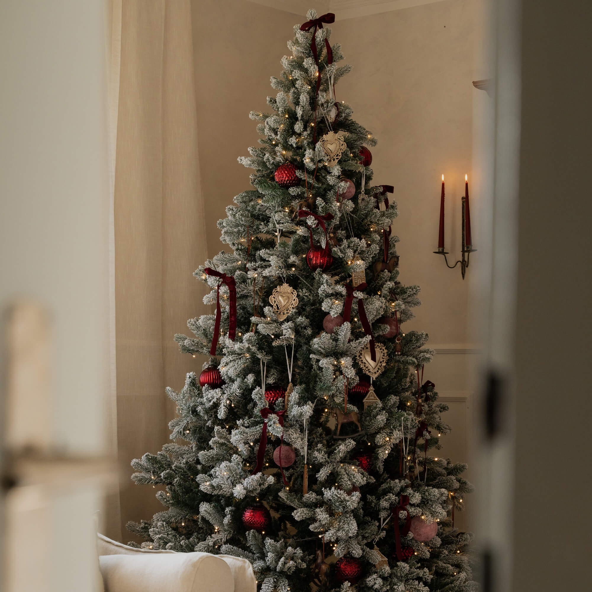 Albero di Natale innevato con decorazioni rosse e beige e luci calde decorative