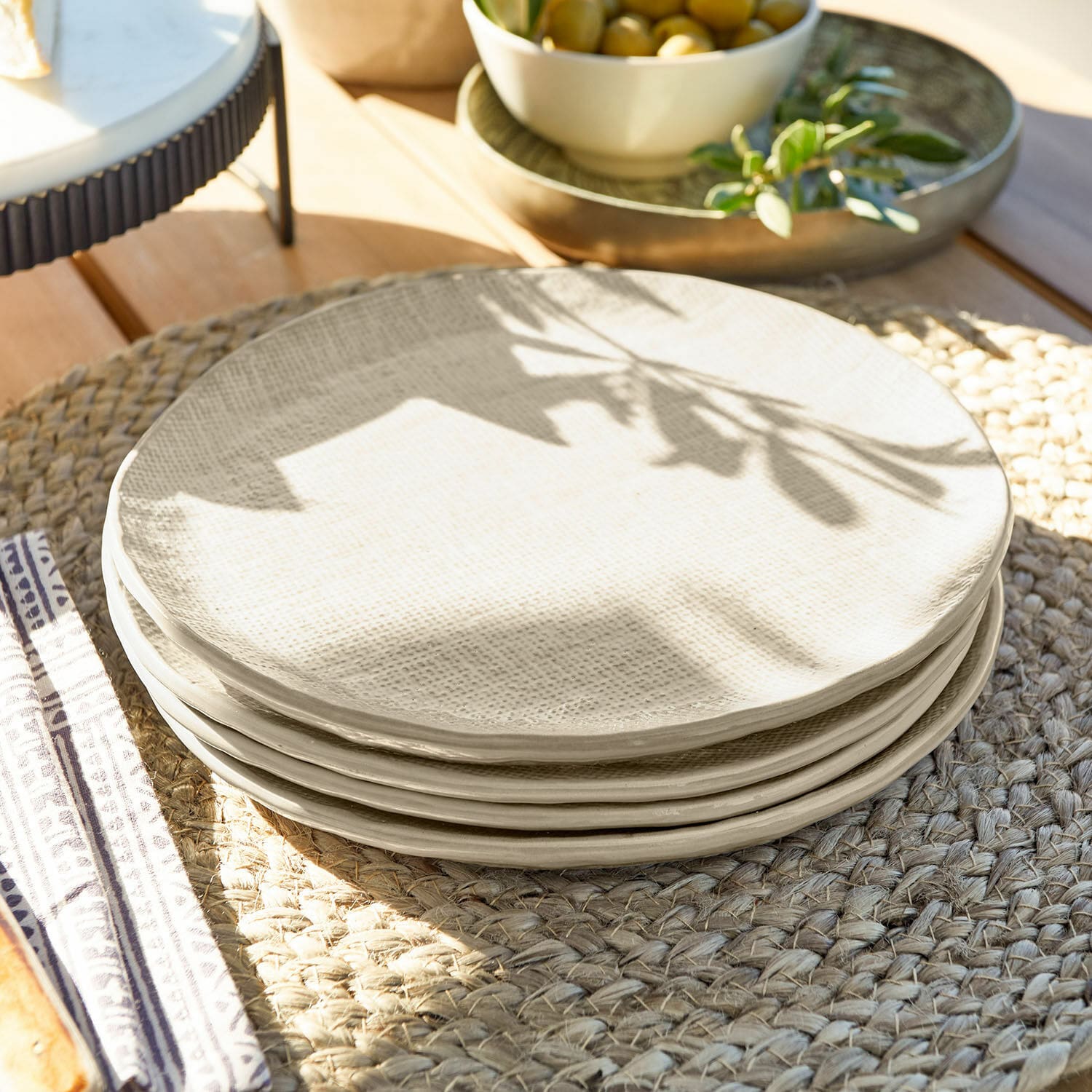 Set di 4 piattini Luganville Set di piatti in ceramica crema con texture su tovaglietta intrecciata in legno