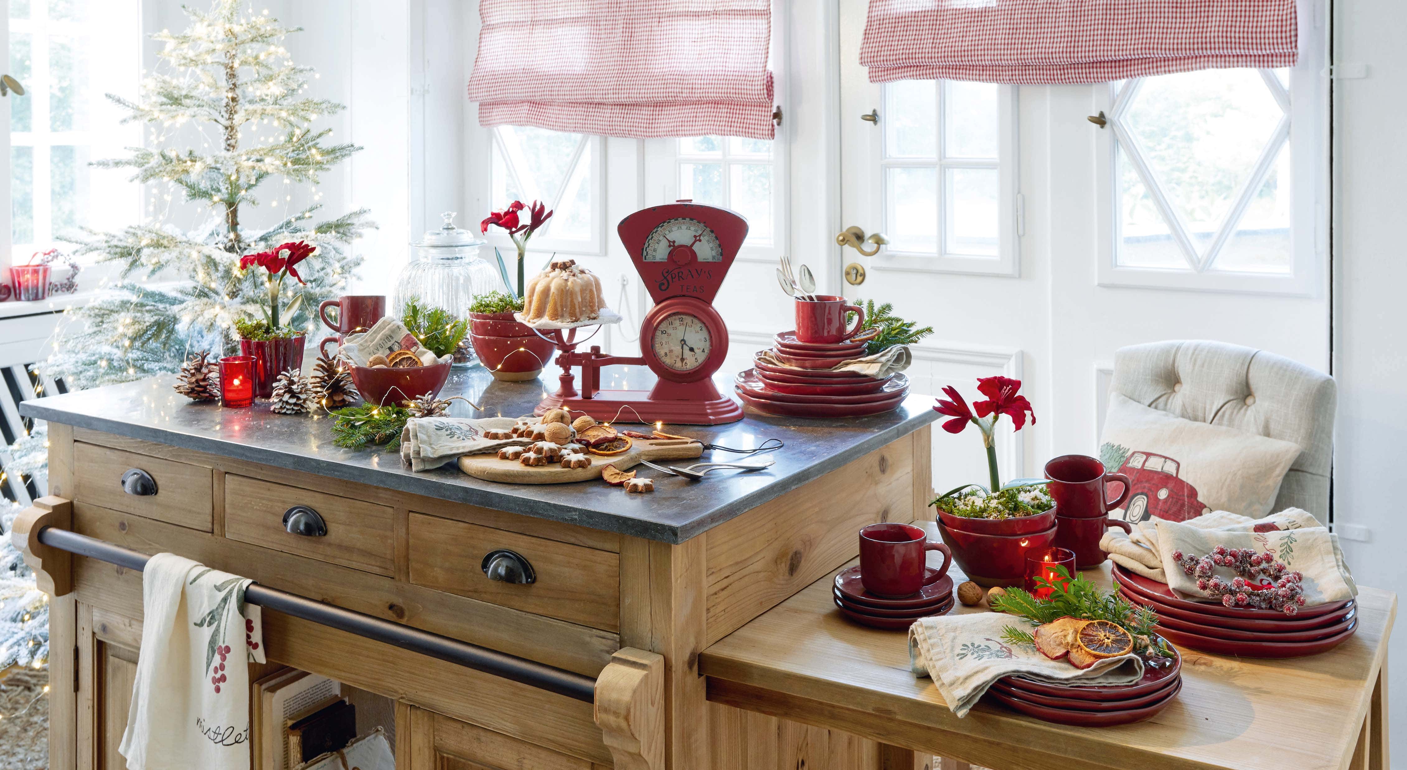 Cucina con isola in legno, stoviglie rosse in ceramica e decorazioni natalizie con luci LED