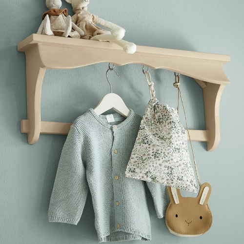 Mensola da parete beige in legno con ganci, con maglione azzurro e borsa a fiori appesi