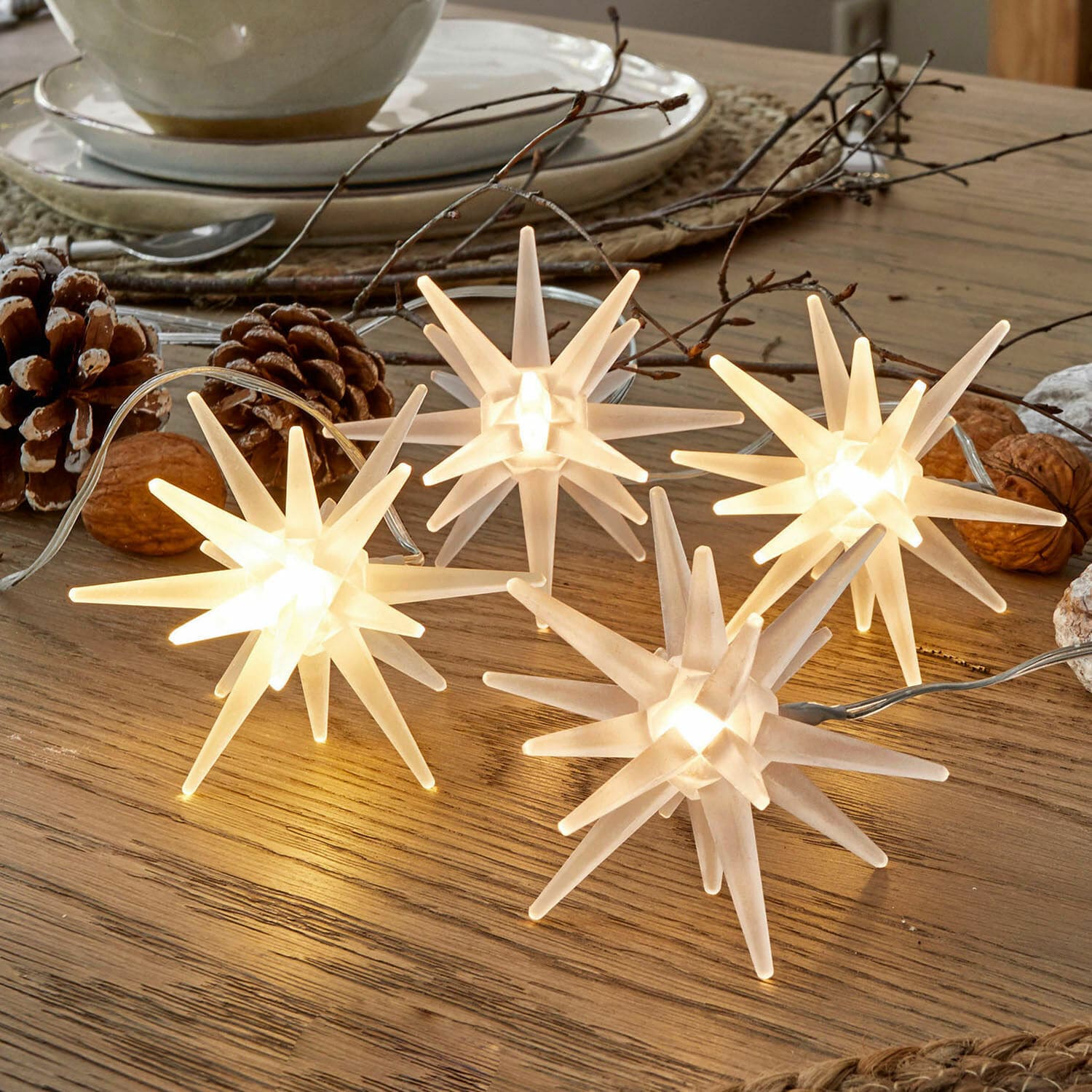 Set di 4 stelle a LED Ciseau Catena luminosa decorativa a forma di stelle bianche in plastica su tavolo in legno con decorazioni naturali