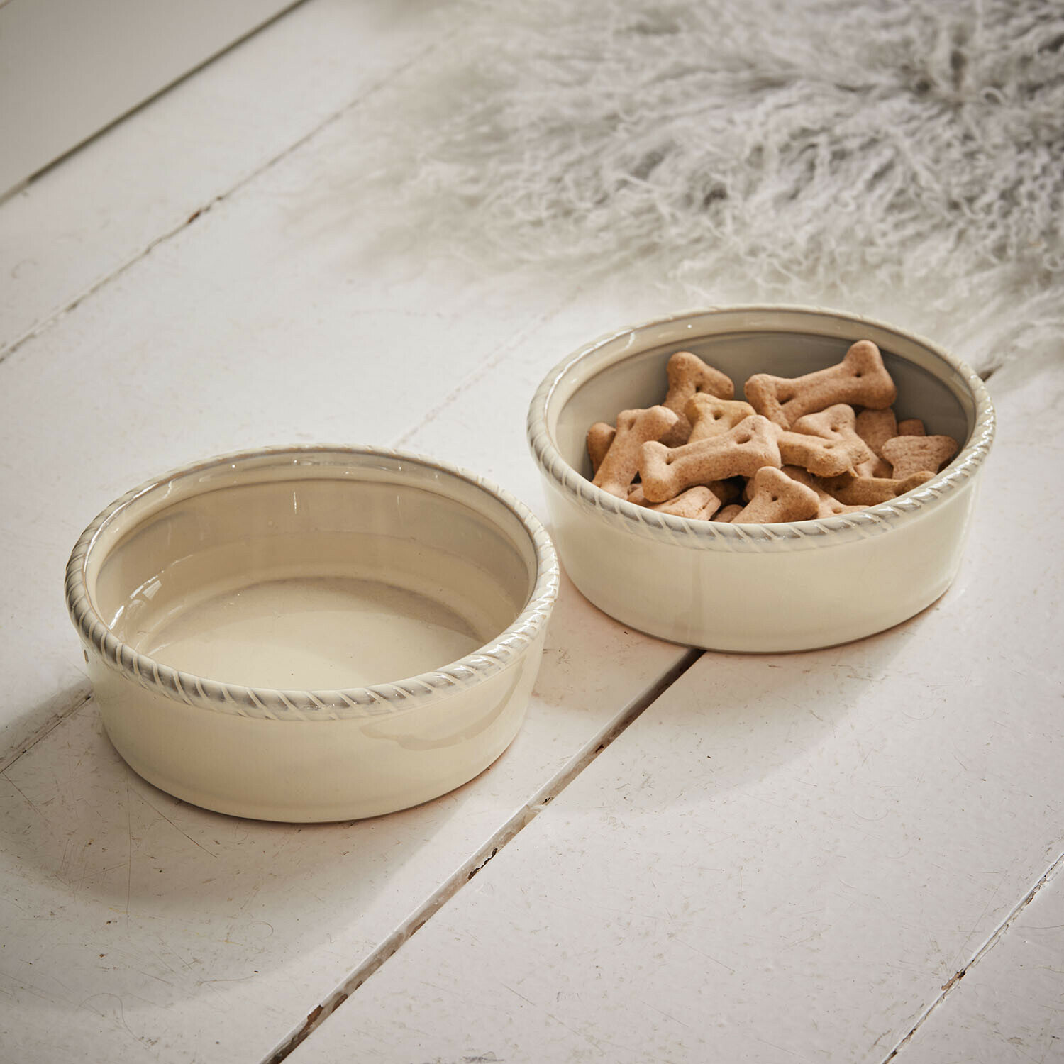 Coppia di ciotole per animali Pawilo Due ciotole in ceramica crema per cani con bordo decorativo su pavimento in legno bianco
