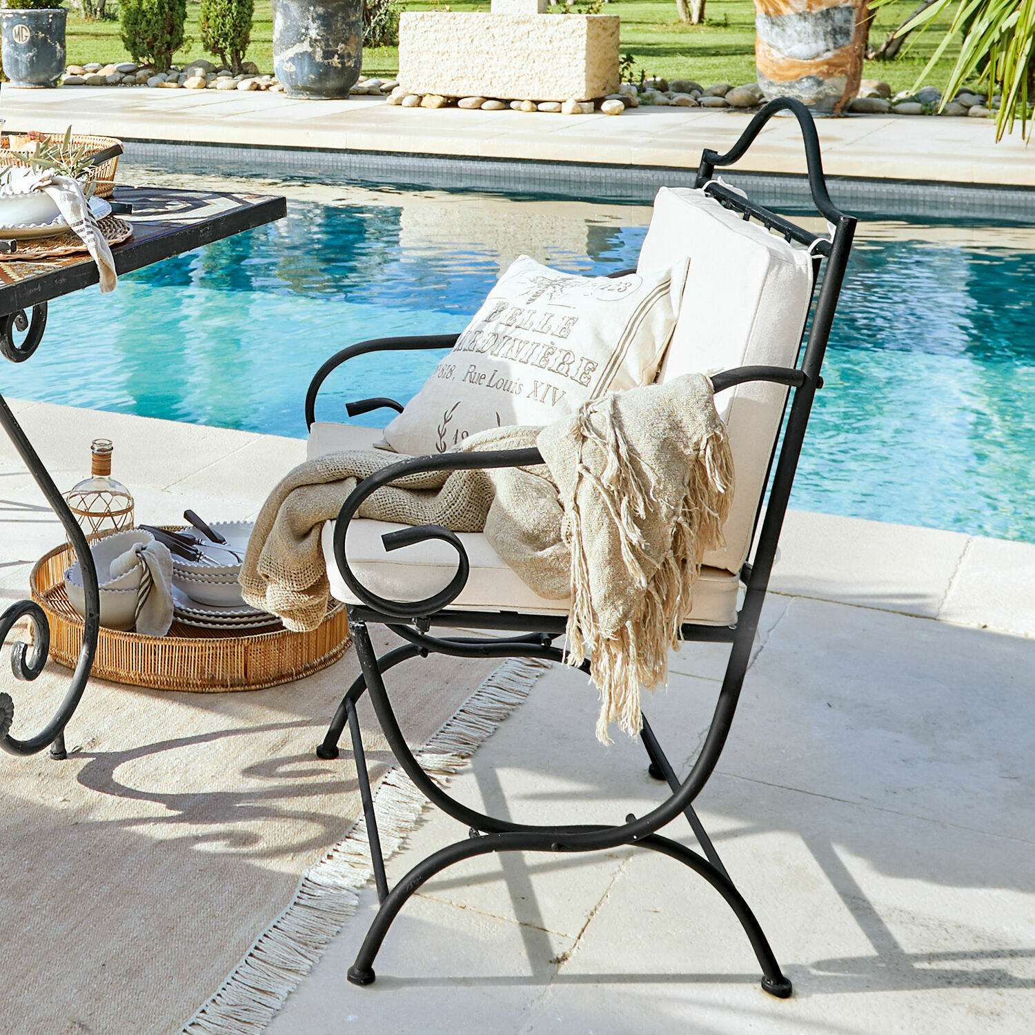 Sedia Avanton Sedia da giardino in metallo nero con cuscino crema e coperta beige vicino alla piscina, mobili da esterno