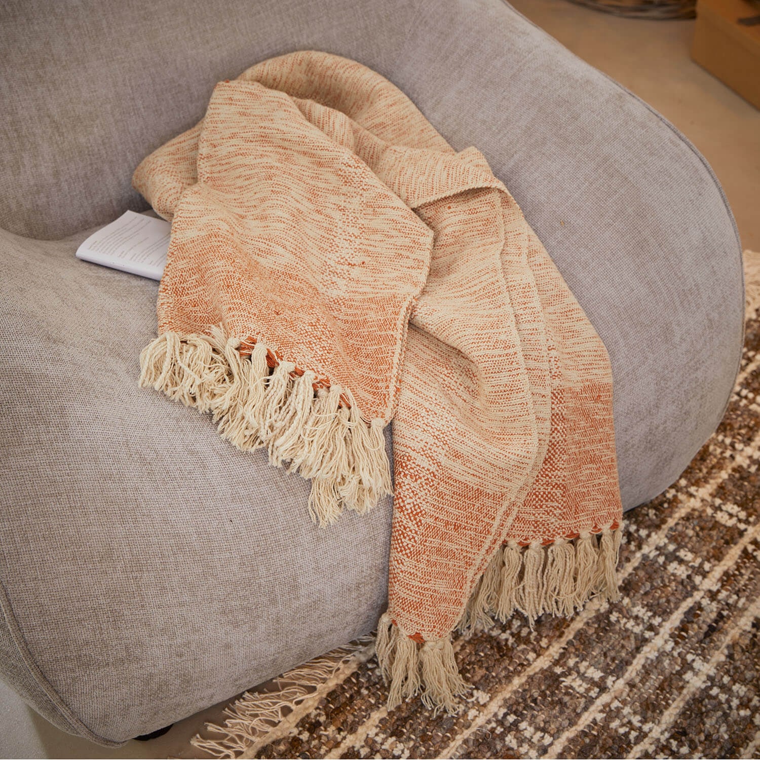 Coperta beige e arancione con frange su divano grigio, tessuto morbido per decorazione casa