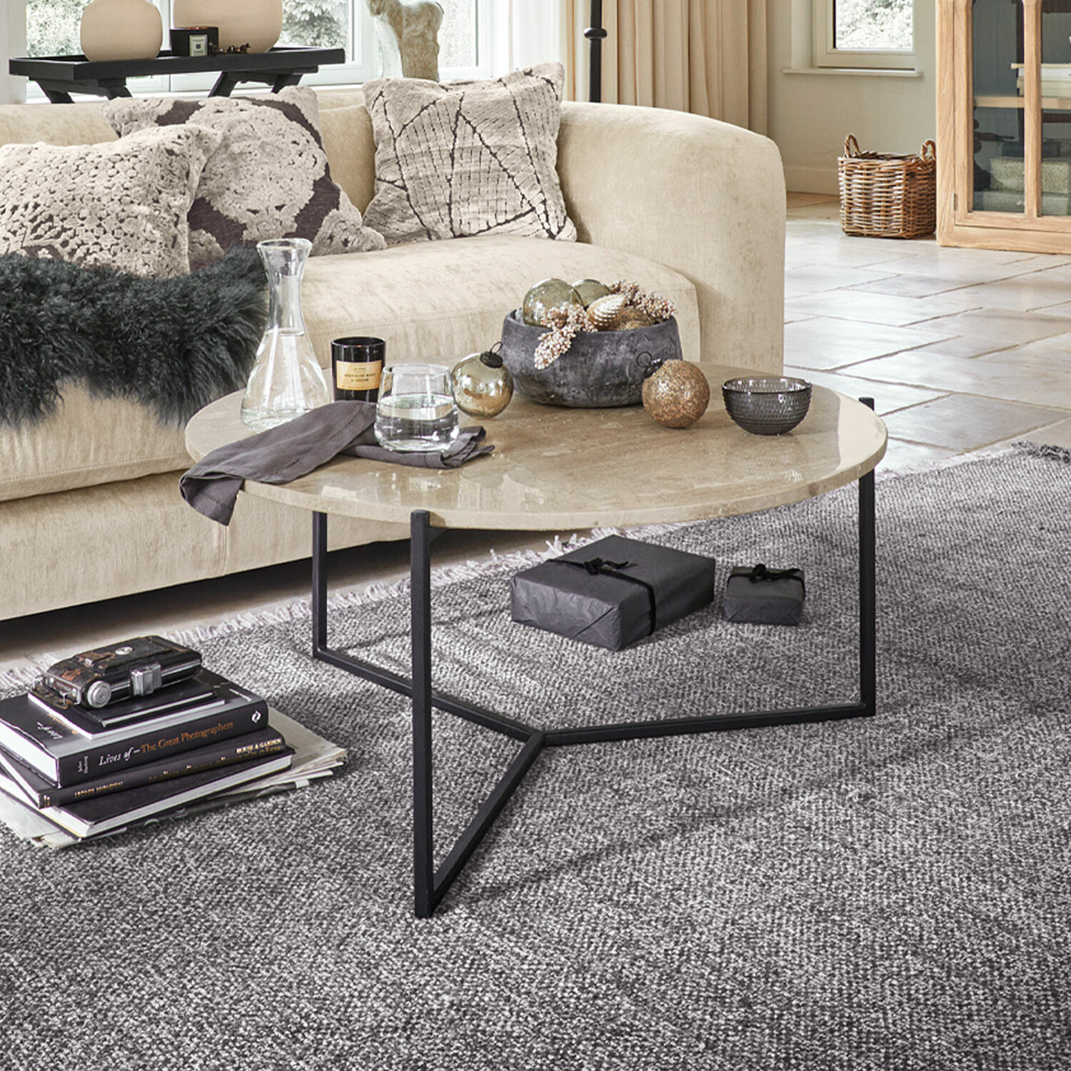 Tavolino da salotto Émorieux Tavolino rotondo con piano in marmo beige e base in metallo nero su tappeto grigio