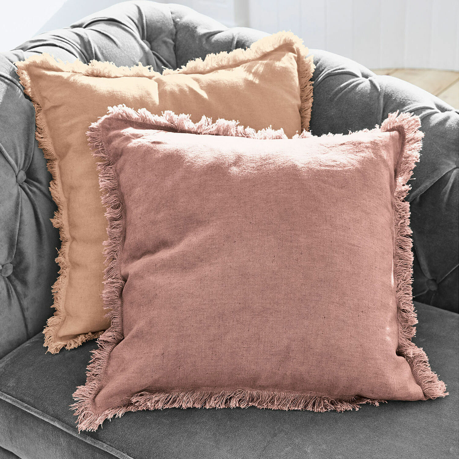 Coppia di copricuscini Quebo Set di due cuscini decorativi in lino con frange rosa e beige su divano grigio