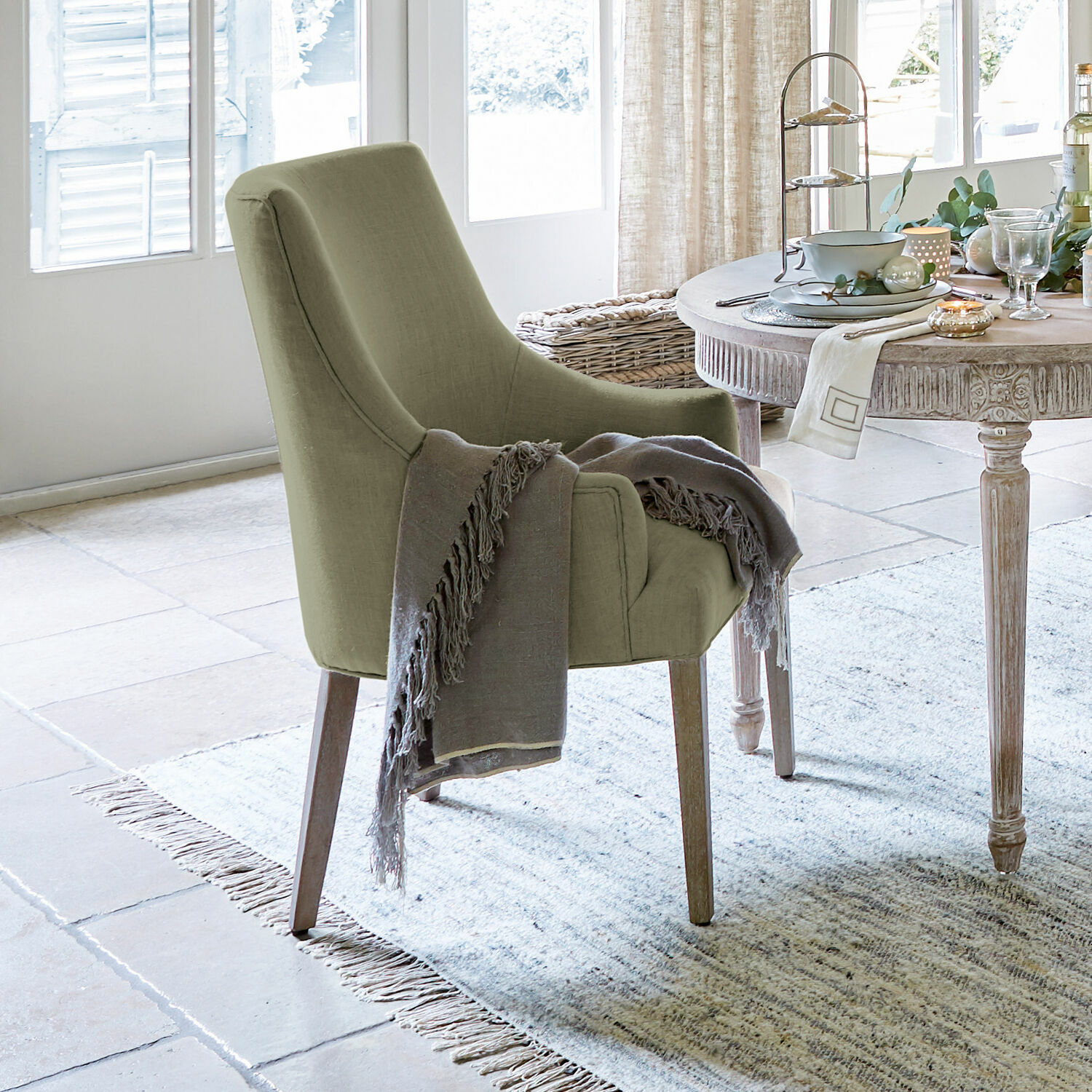 Sedia Hyeres Sedia imbottita verde con gambe in legno e coperta grigia in soggiorno luminoso con tappeto