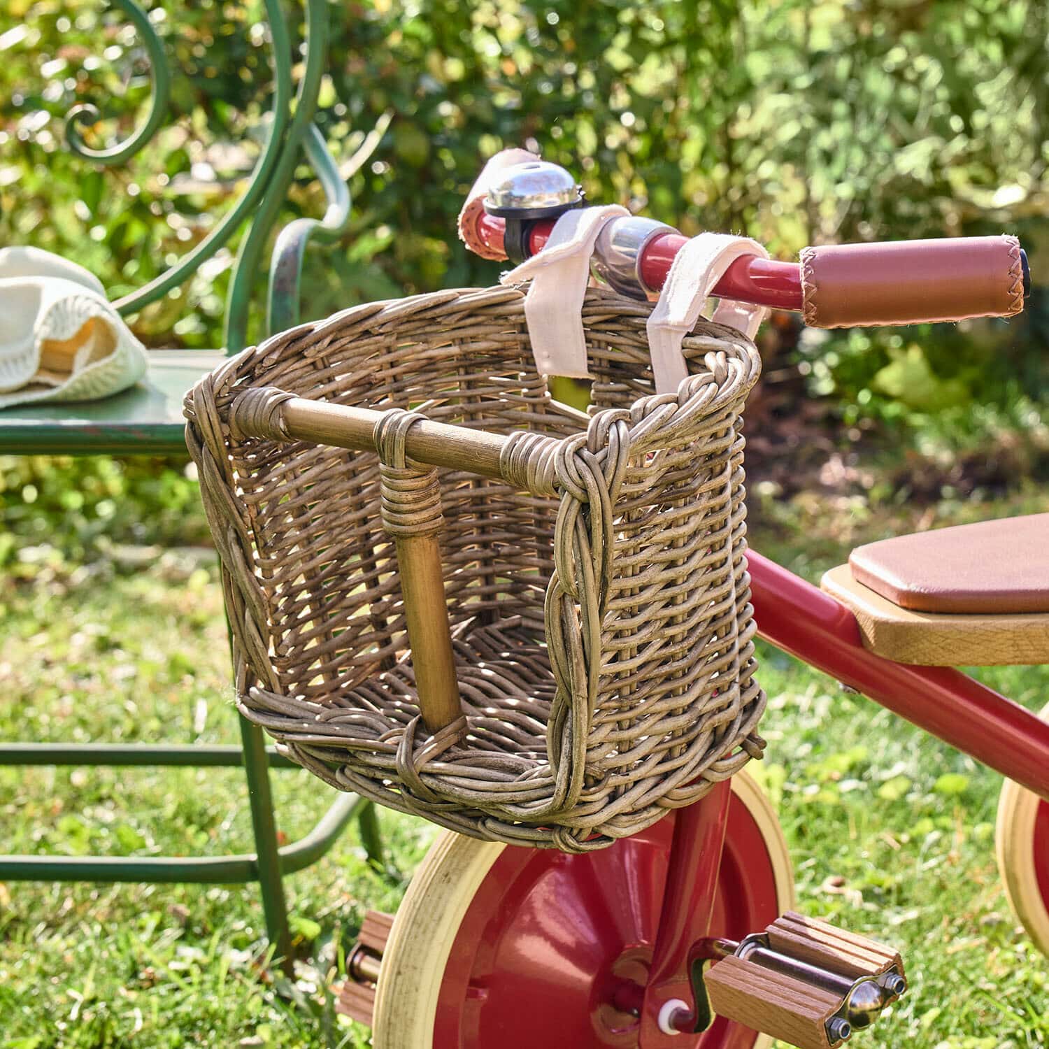 Seggiolino per bambole Snokki Cestino in vimini su bicicletta rossa per bambini con manopole in pelle, su prato in giardino