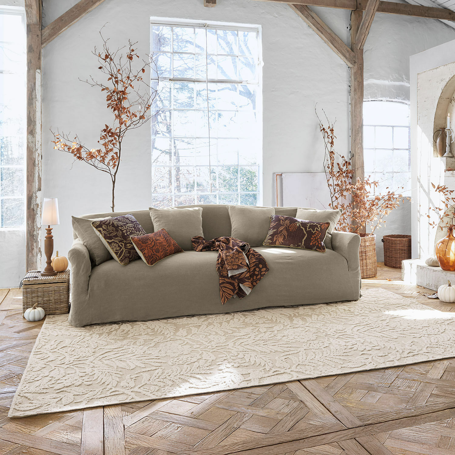 Tappeto Azimra Divano beige in tessuto in soggiorno luminoso con cuscini decorativi e tappeto con motivo foglie