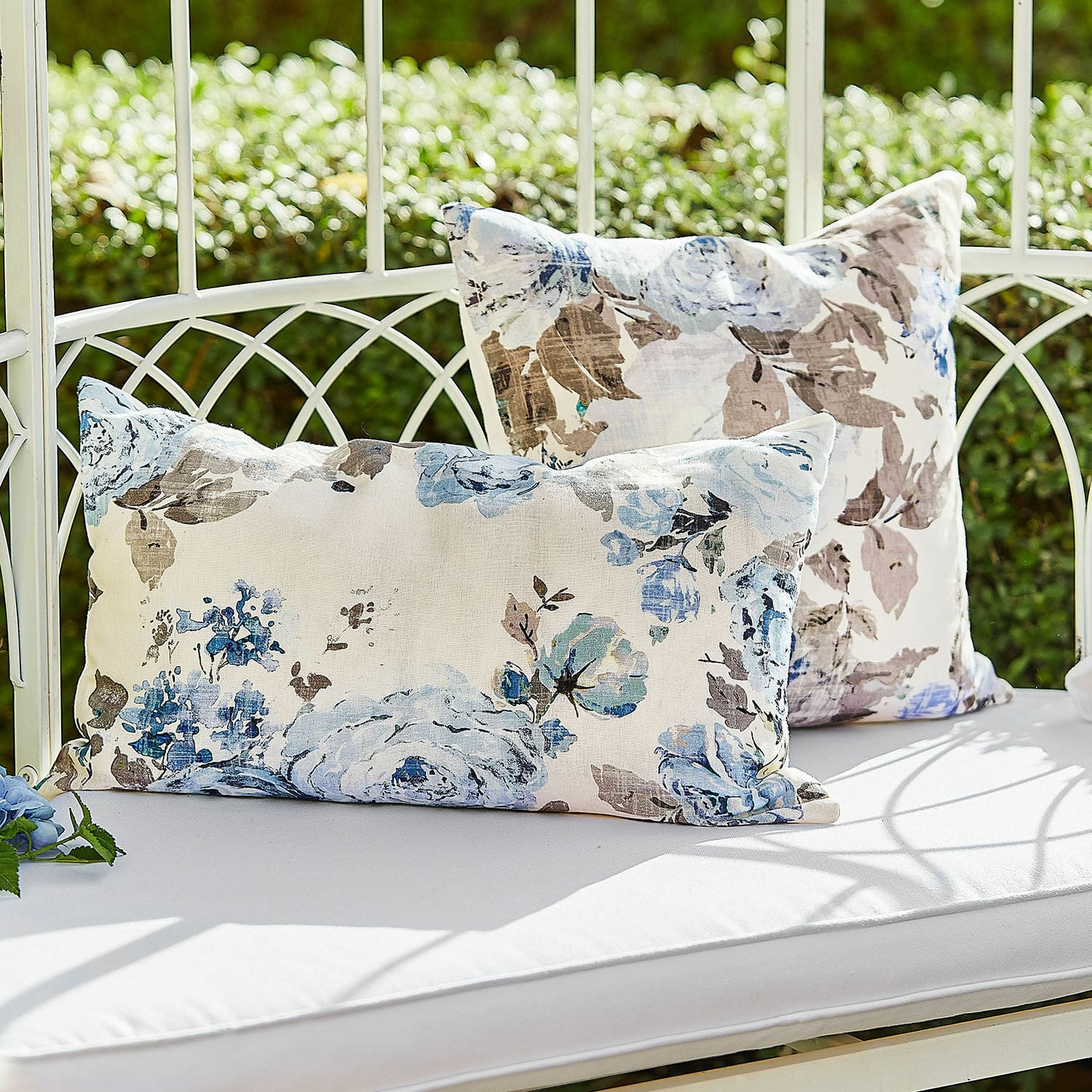 Coppia di copricuscini Cloranne Cuscini decorativi in cotone con motivo floreale blu e marrone su panca bianca all'aperto