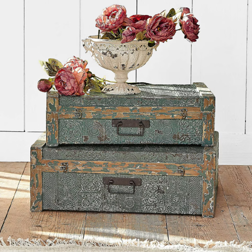 Set di due bauli decorativi in metallo verde con una coppa floreale sopra