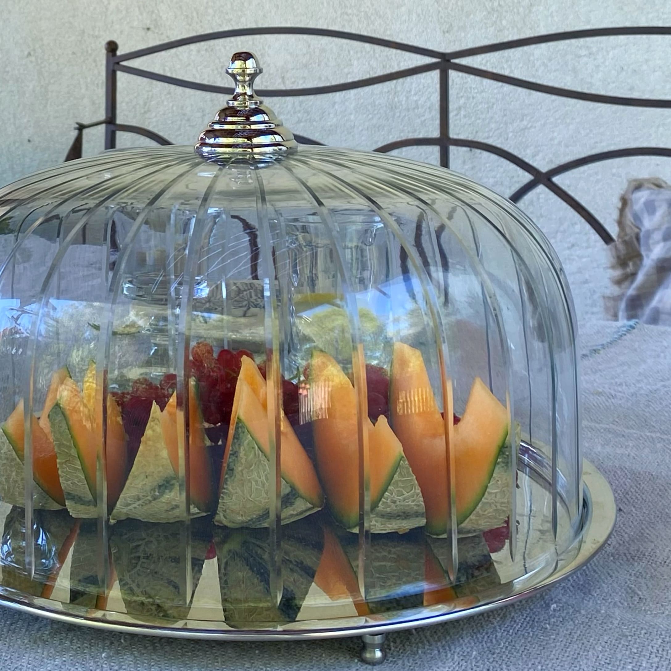 Campana di vetro con manico argentato che copre frutta tagliata su un tavolo