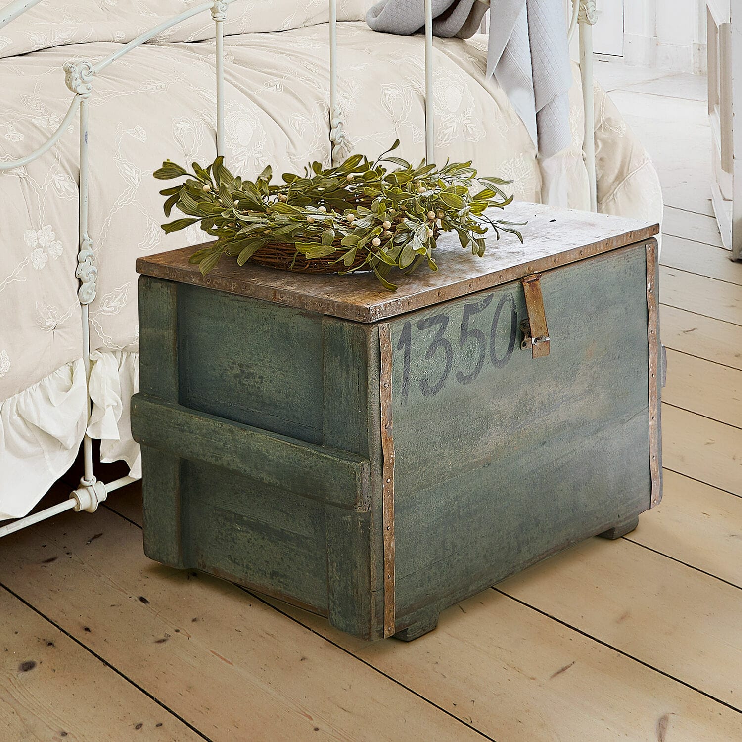 Baule Lorive Cassa metallica verde con numero 1350 e decorazione di foglie verdi su pavimento in legno chiaro
