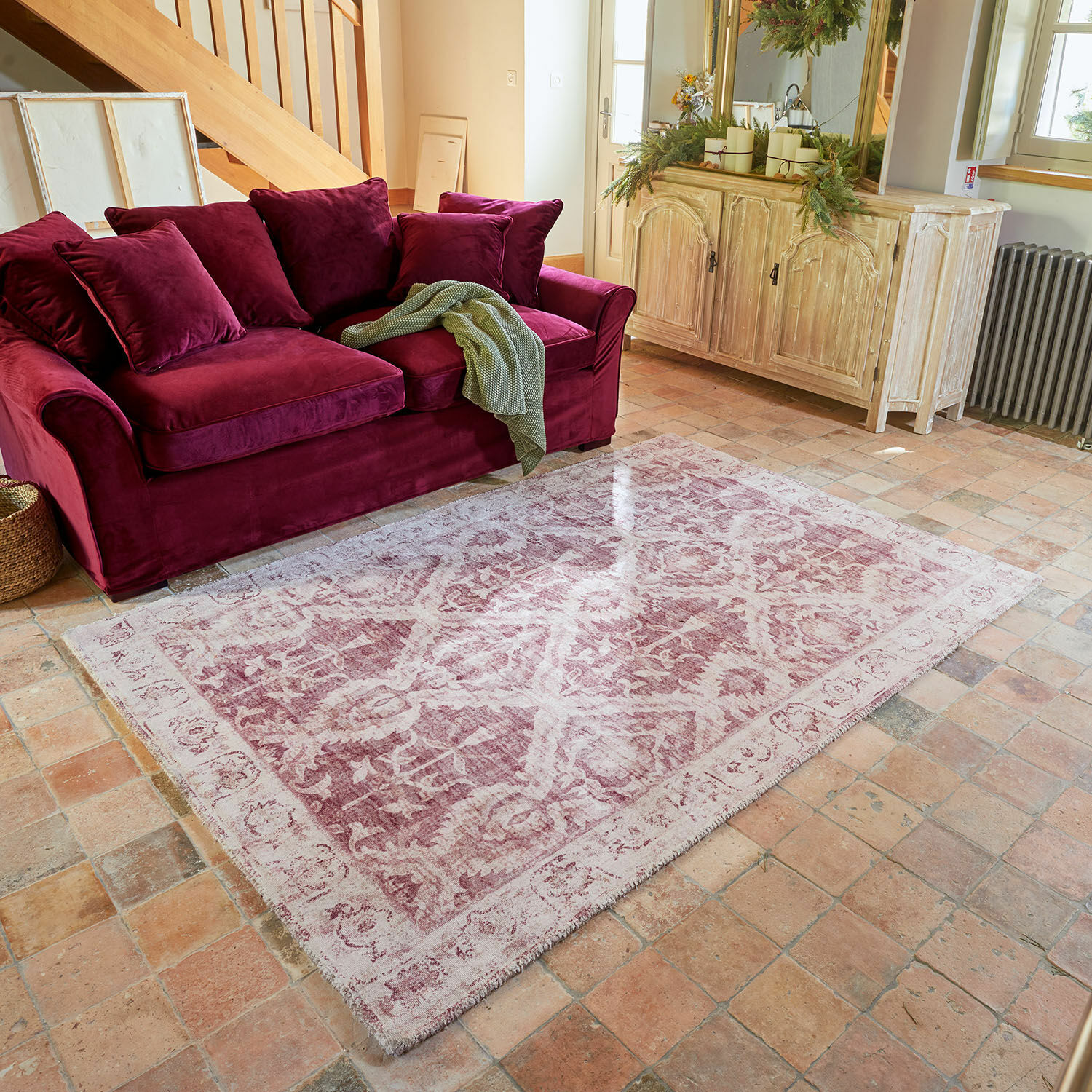 Tappeto Mirellis Tappeto rosa vintage con motivo davanti a divano in velluto bordeaux e credenza in legno chiaro