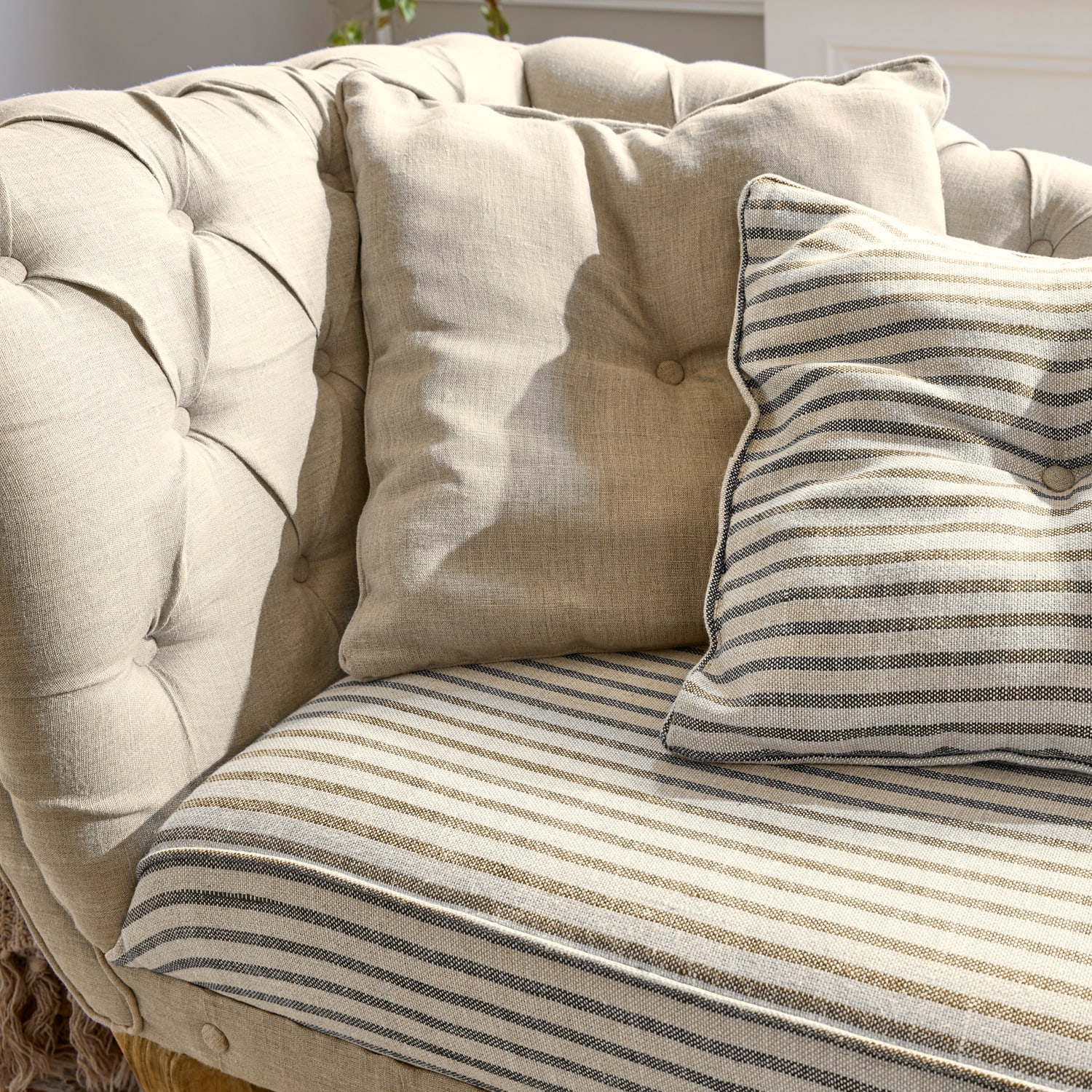 Divano beige imbottito con cuscini a righe e tinta unita, tessuto morbido, mobile confortevole