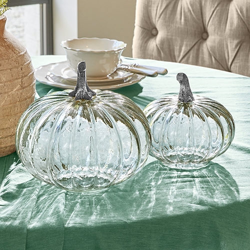 Decorazioni in vetro a forma di zucche con gambi metallici su tovaglia verde, ornamento da tavola