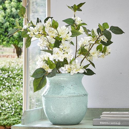 Vaso in ceramica verde menta con fiori bianchi su tavolo, decorazione naturale per interni