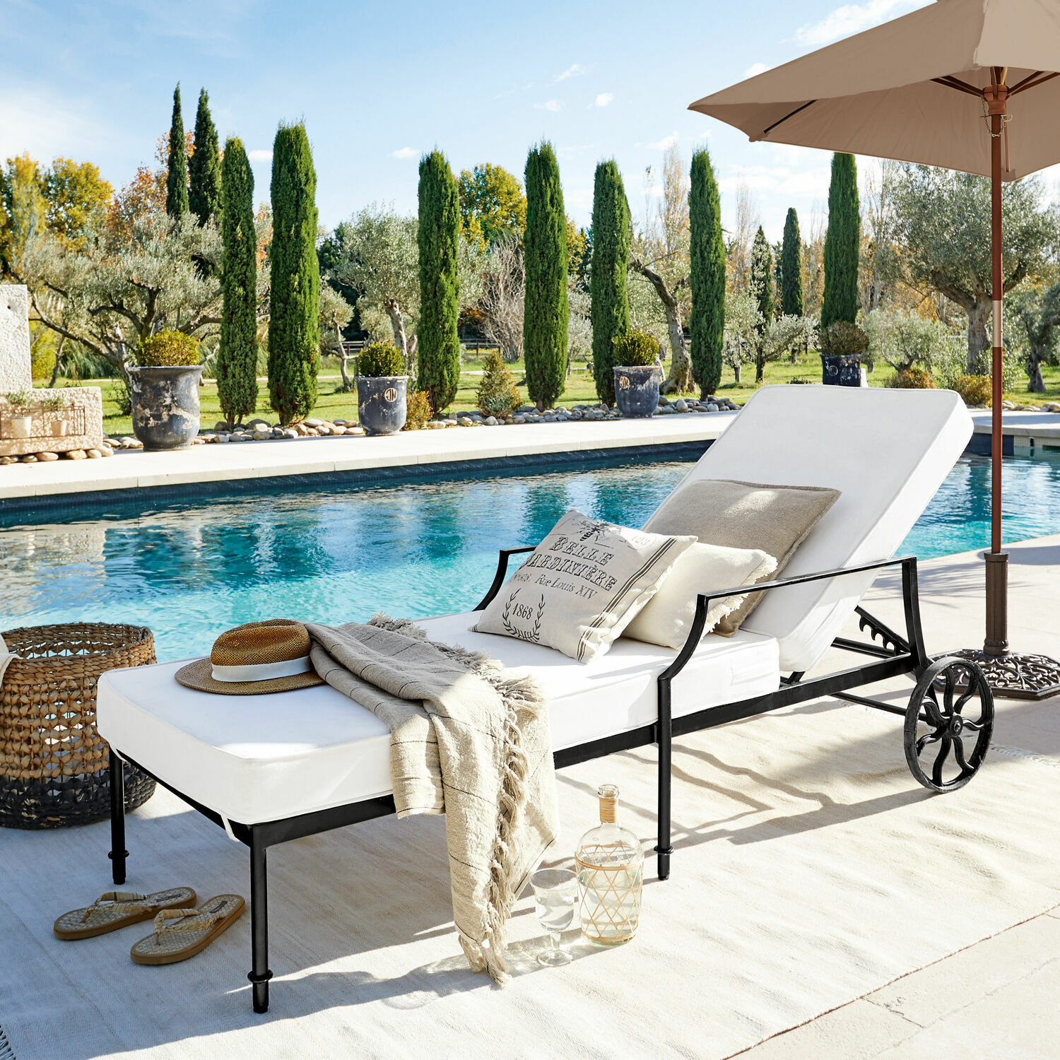 Chaise-longue Vienne Lettino da giardino con cuscino bianco e struttura in metallo nero vicino alla piscina in giardino soleggiato