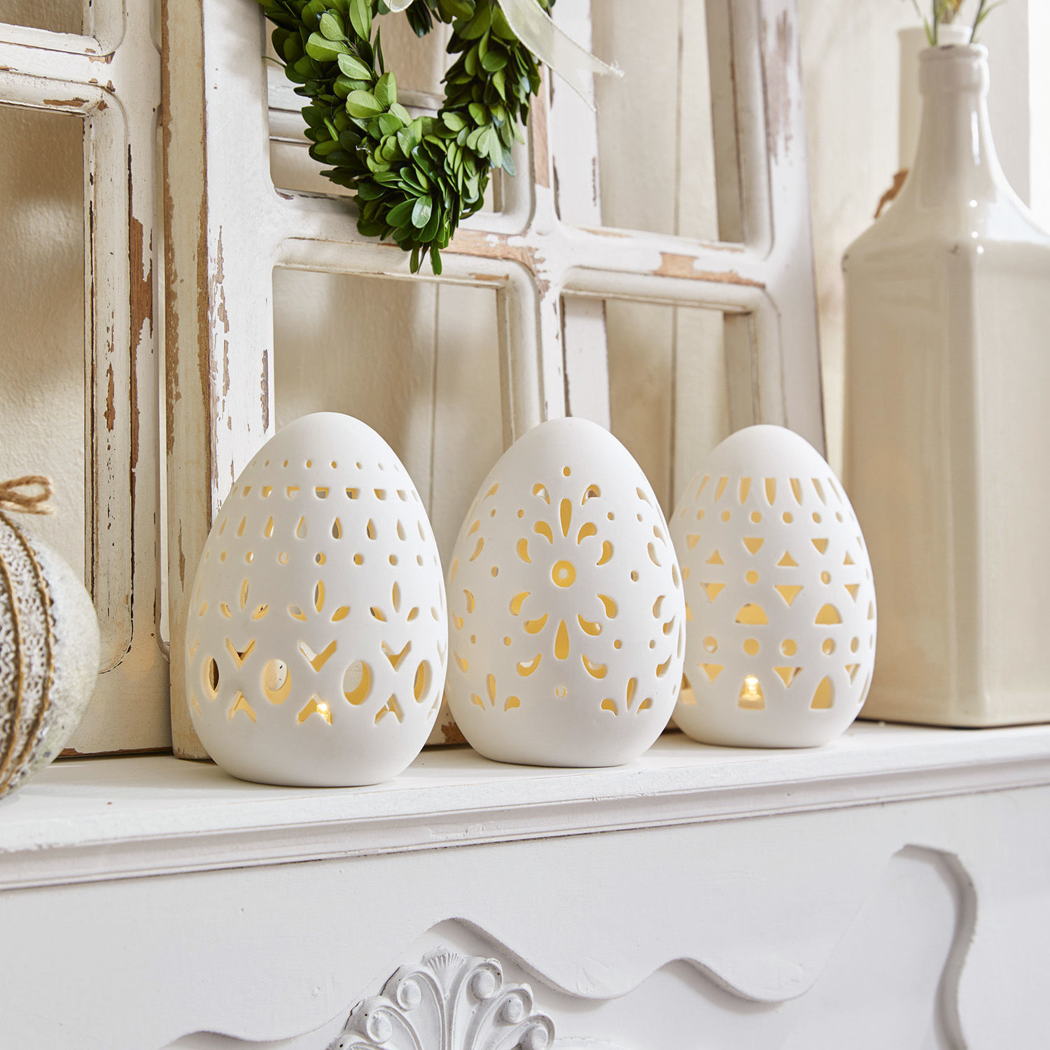 Set di 3 uova di Pasqua Mouna Set di tre portacandele in ceramica bianca a forma di uovo con motivo traforato su camino