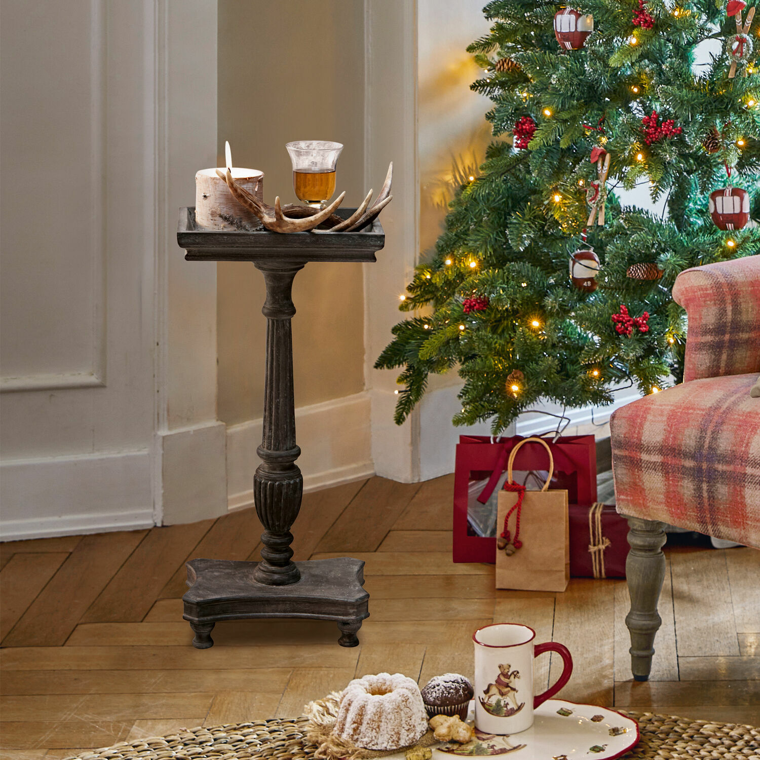 Supporto in legno scuro con candela e decorazione di corna vicino all'albero di Natale e regali