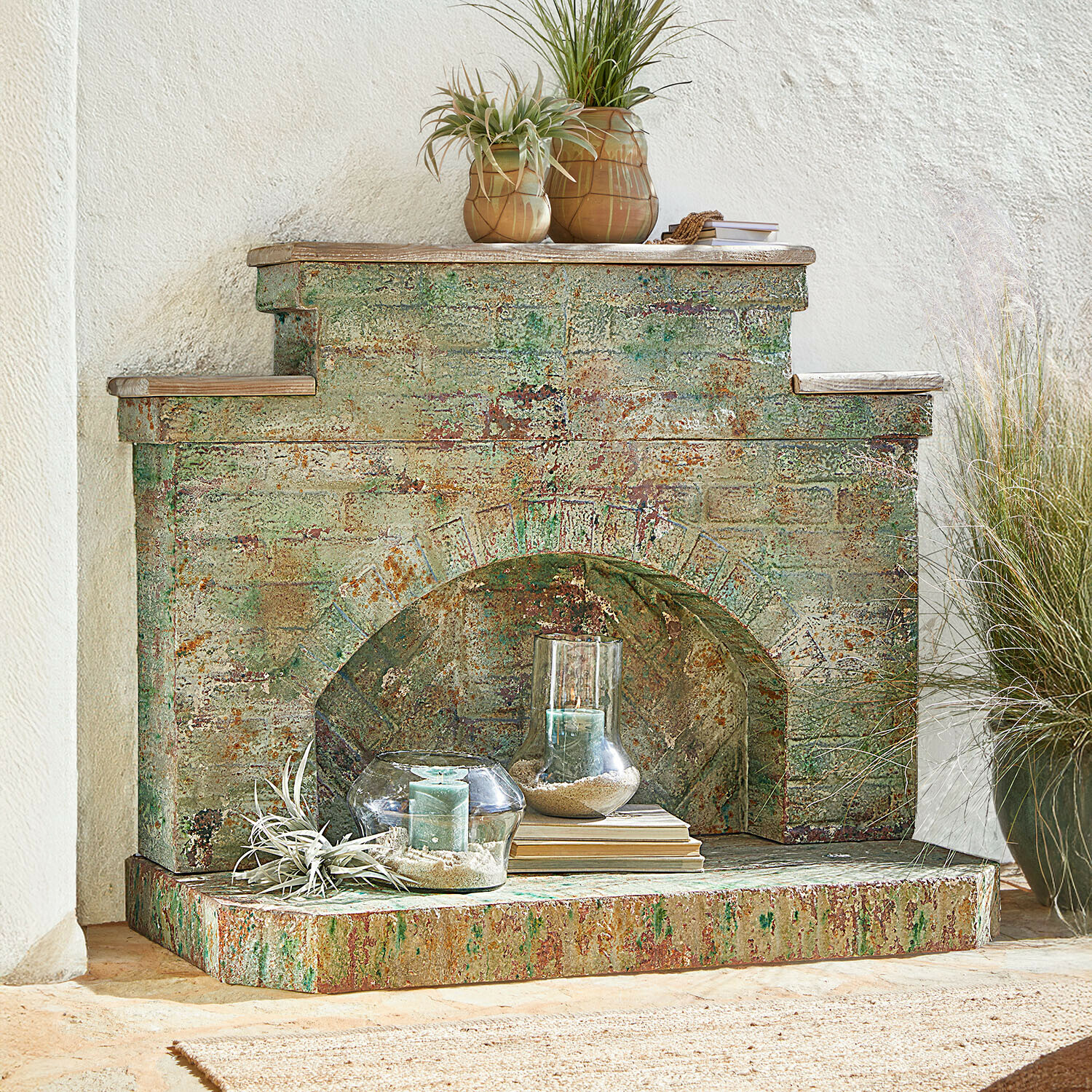 Consolle caminetto Kestonbury Camino decorativo in metallo invecchiato verde ruggine con candele e piante