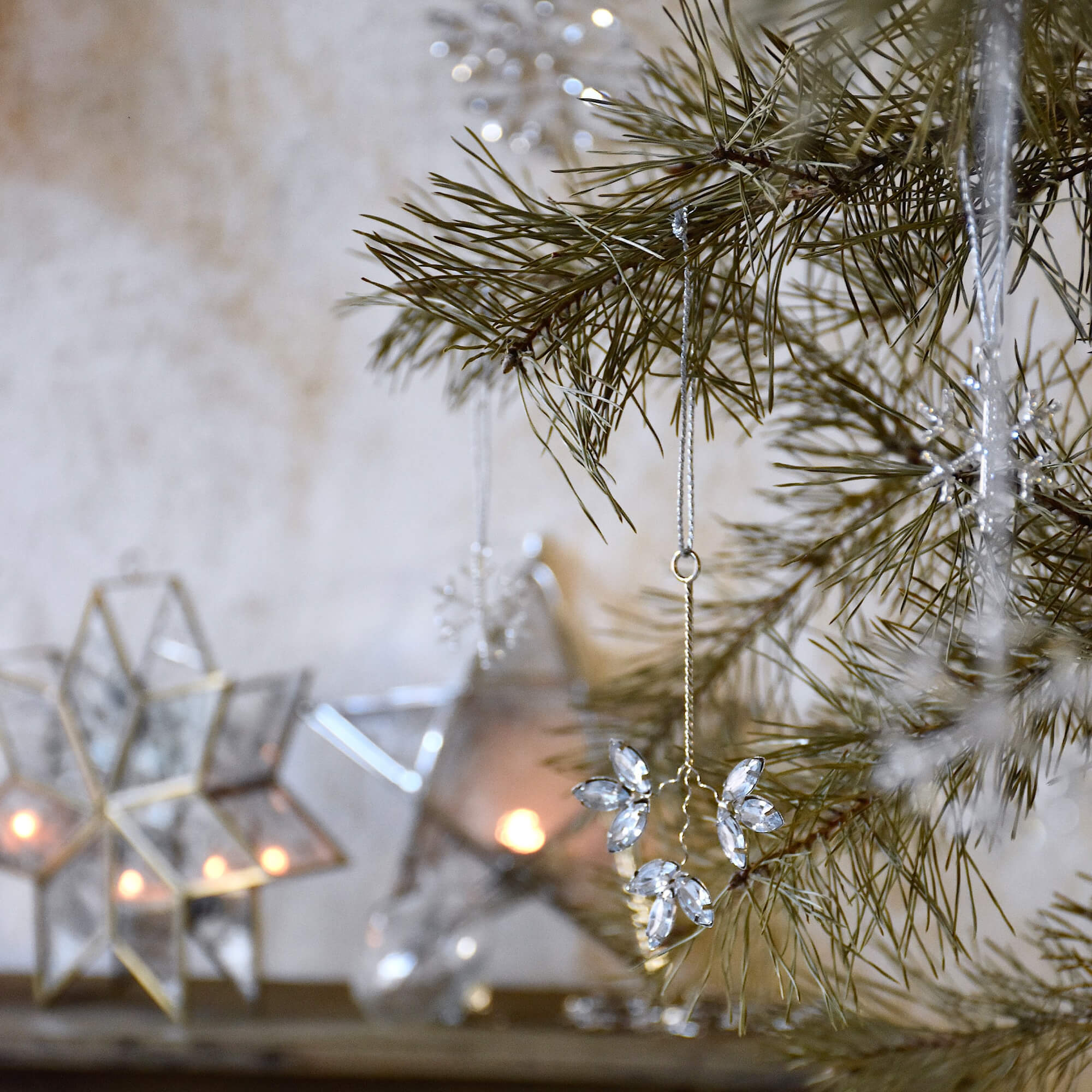 Decorazione natalizia con pendenti di cristallo su ramo di pino e stelle luminose sullo sfondo