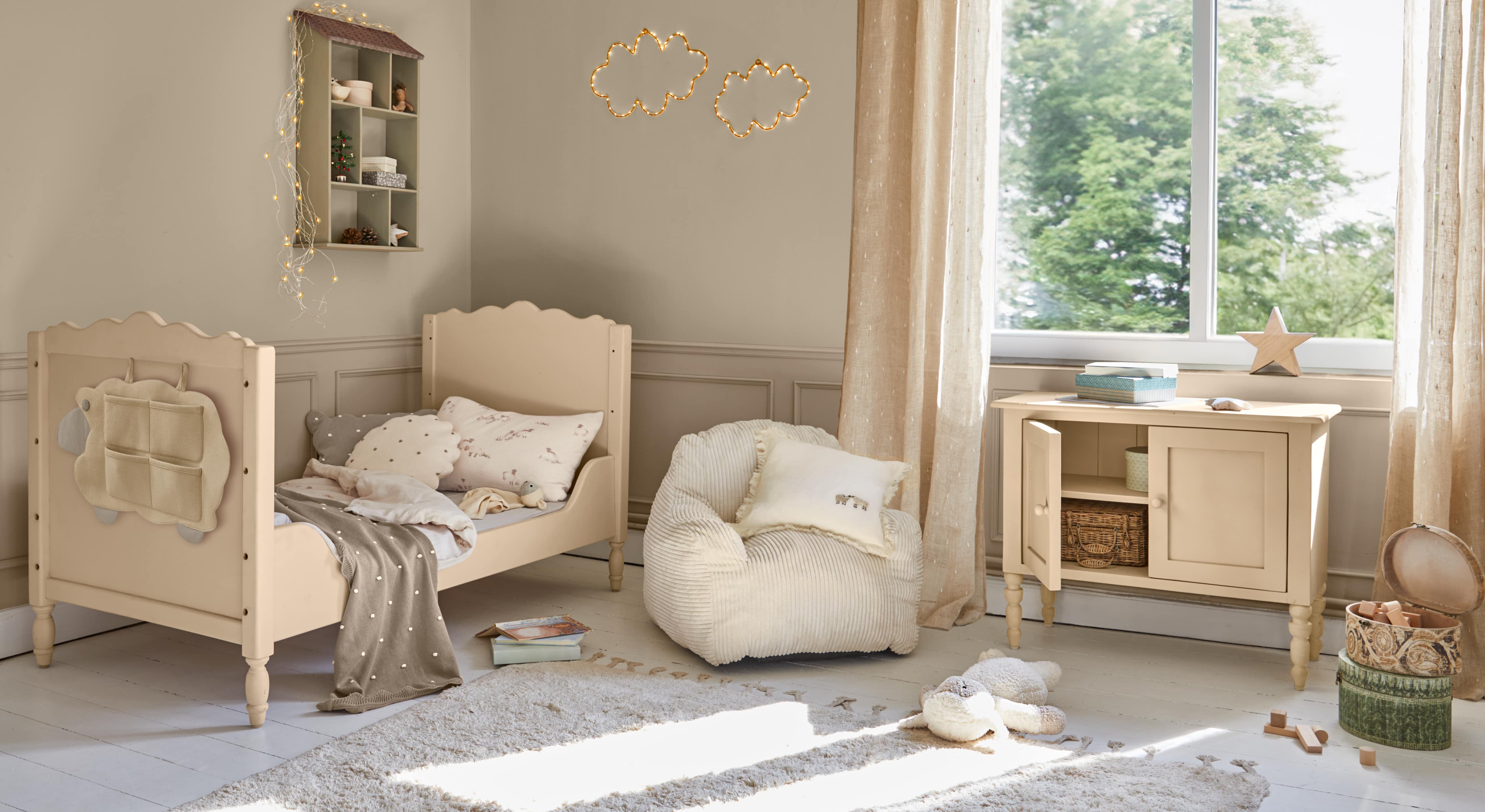 Letto per bambini in legno beige con cuscini morbidi e cassettiera abbinata in stanza luminosa