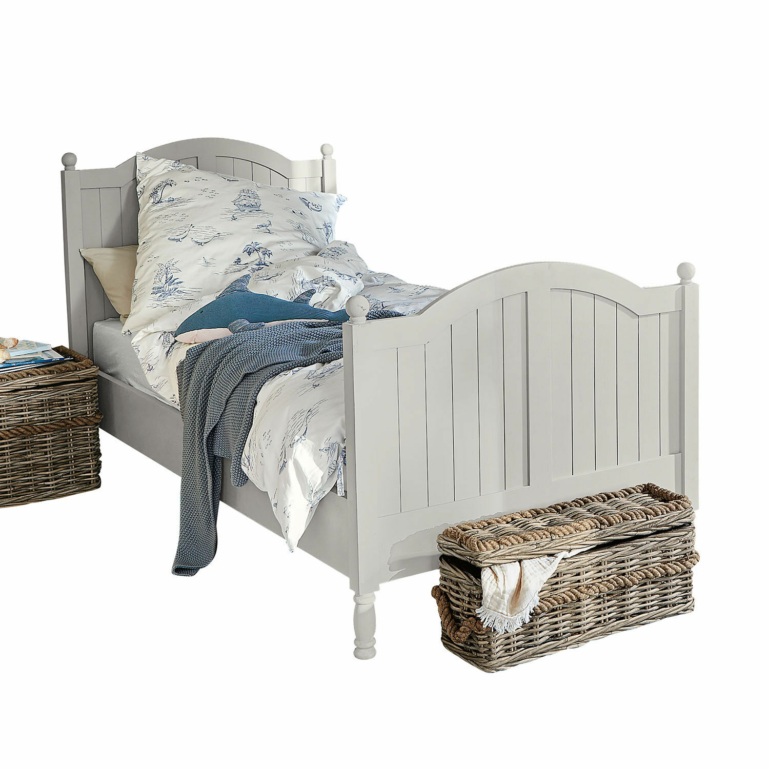Letto Alarion Letto in legno bianco con testiera decorativa, biancheria da letto con motivi blu e cesto di vimini accanto
