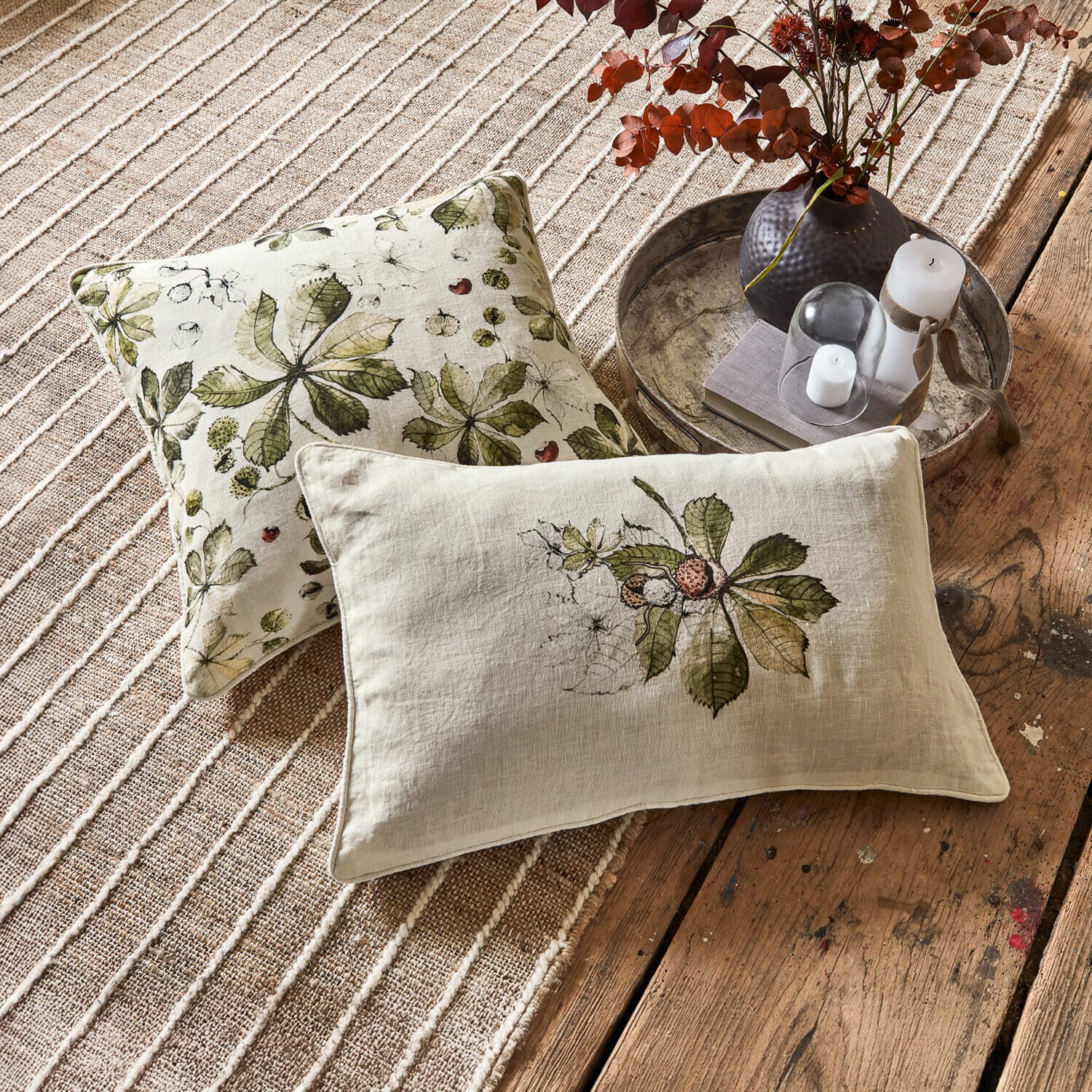 Coppia di copricuscini Elsie Cuscini decorativi in lino con foglie verdi su sfondo beige su tappeto e pavimento in legno