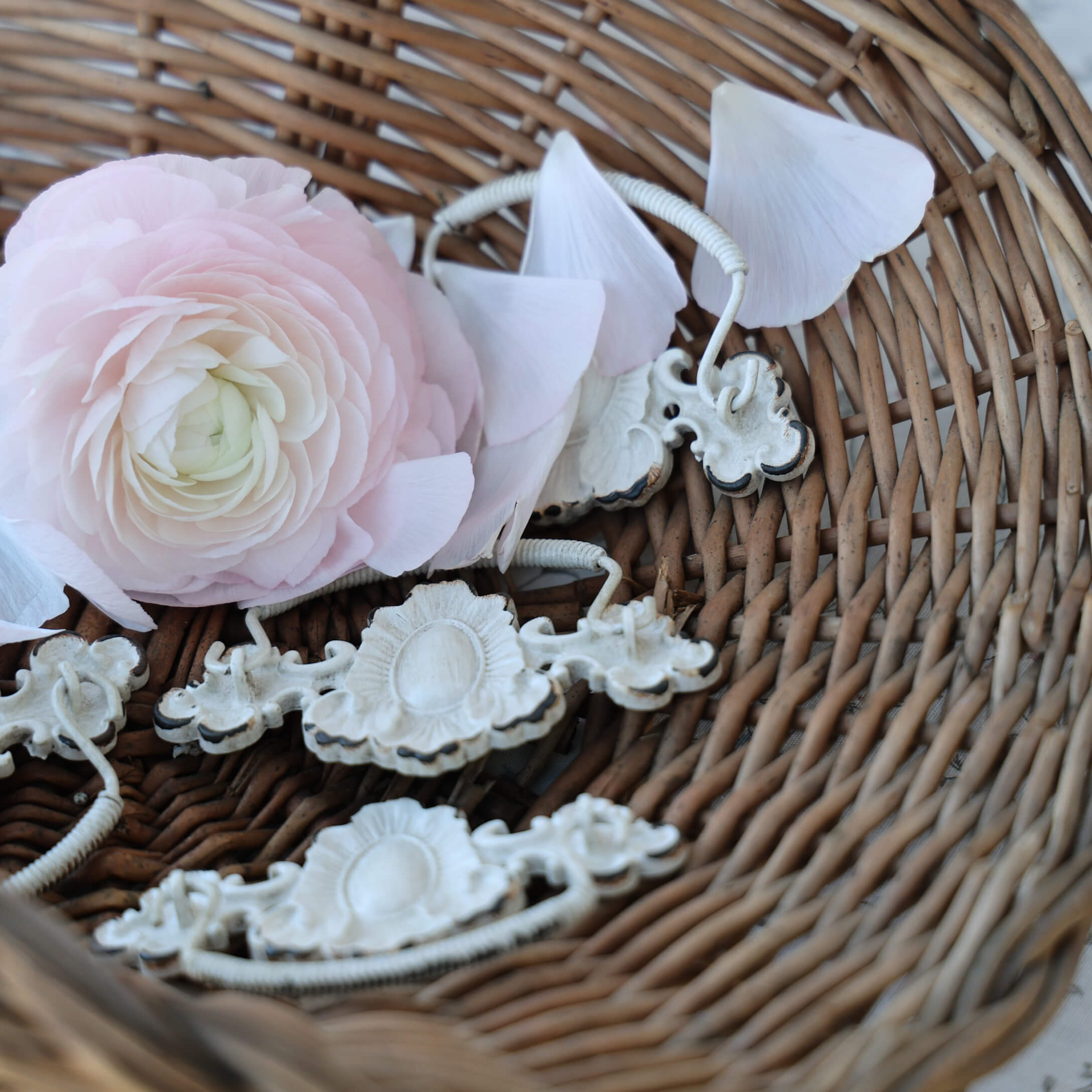 Delicato fiore rosa e maniglie in metallo bianco in cesto di vimini, decorazione d'interni vintage