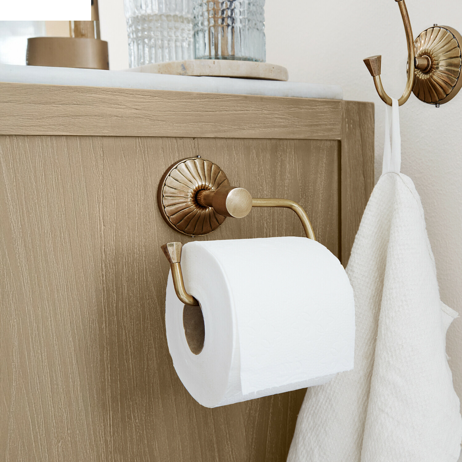 Portarotolo Terling Porta rotolo in ottone con gancio e asciugamano bianco su mobile in legno chiaro