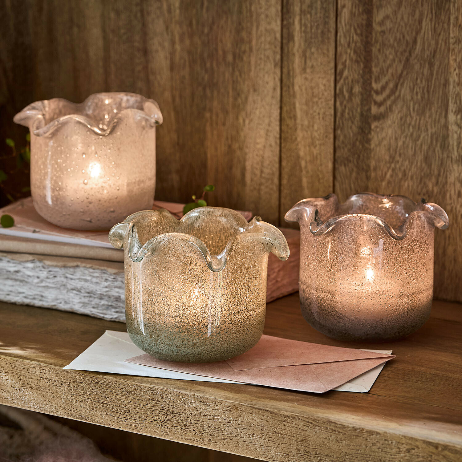 Set di 3 portalumini Venara Tre portacandele decorativi in vetro soffiato dai toni pastello su una mensola in legno