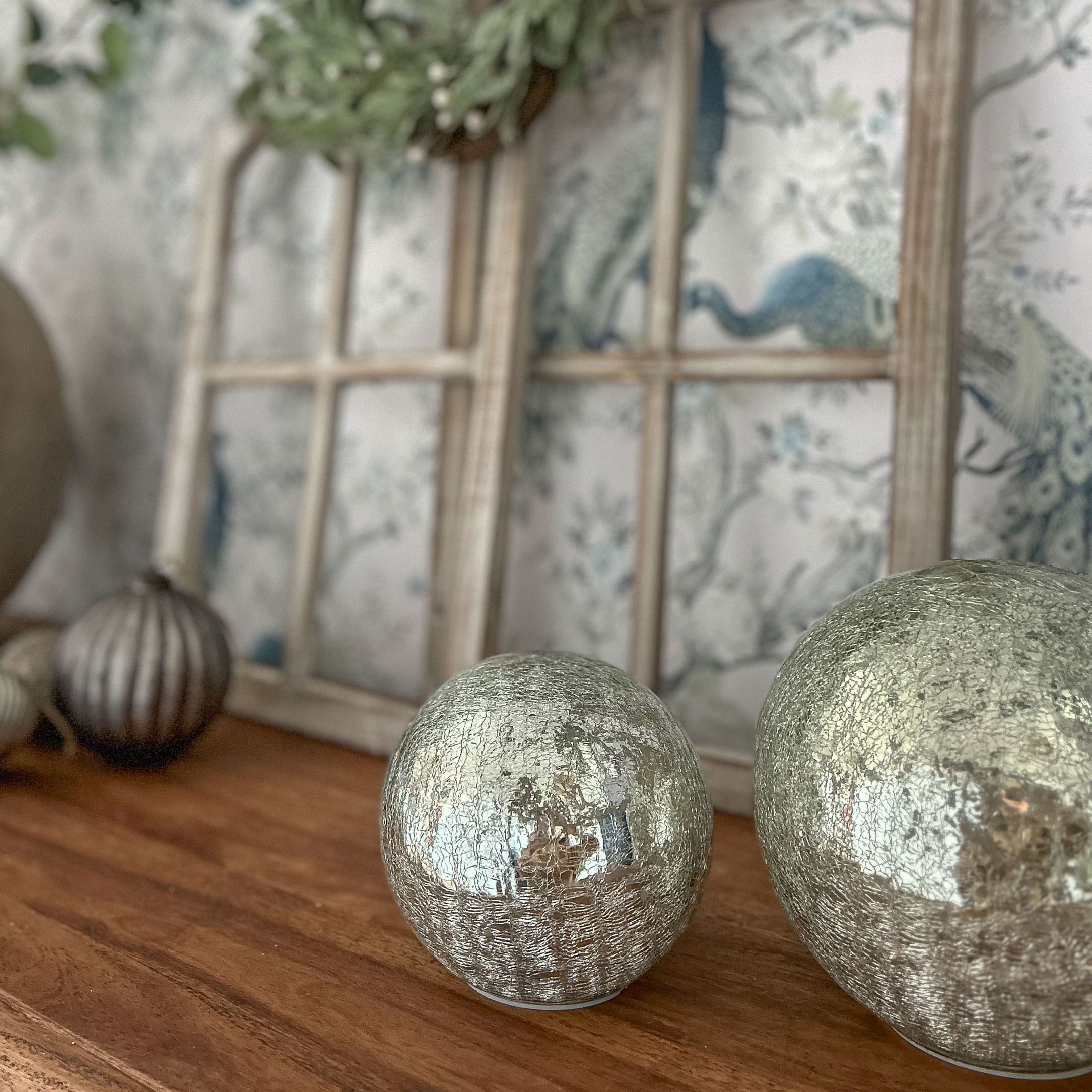 Sfere decorative argentate con superficie screpolata su tavolo in legno per decorazione d'interni