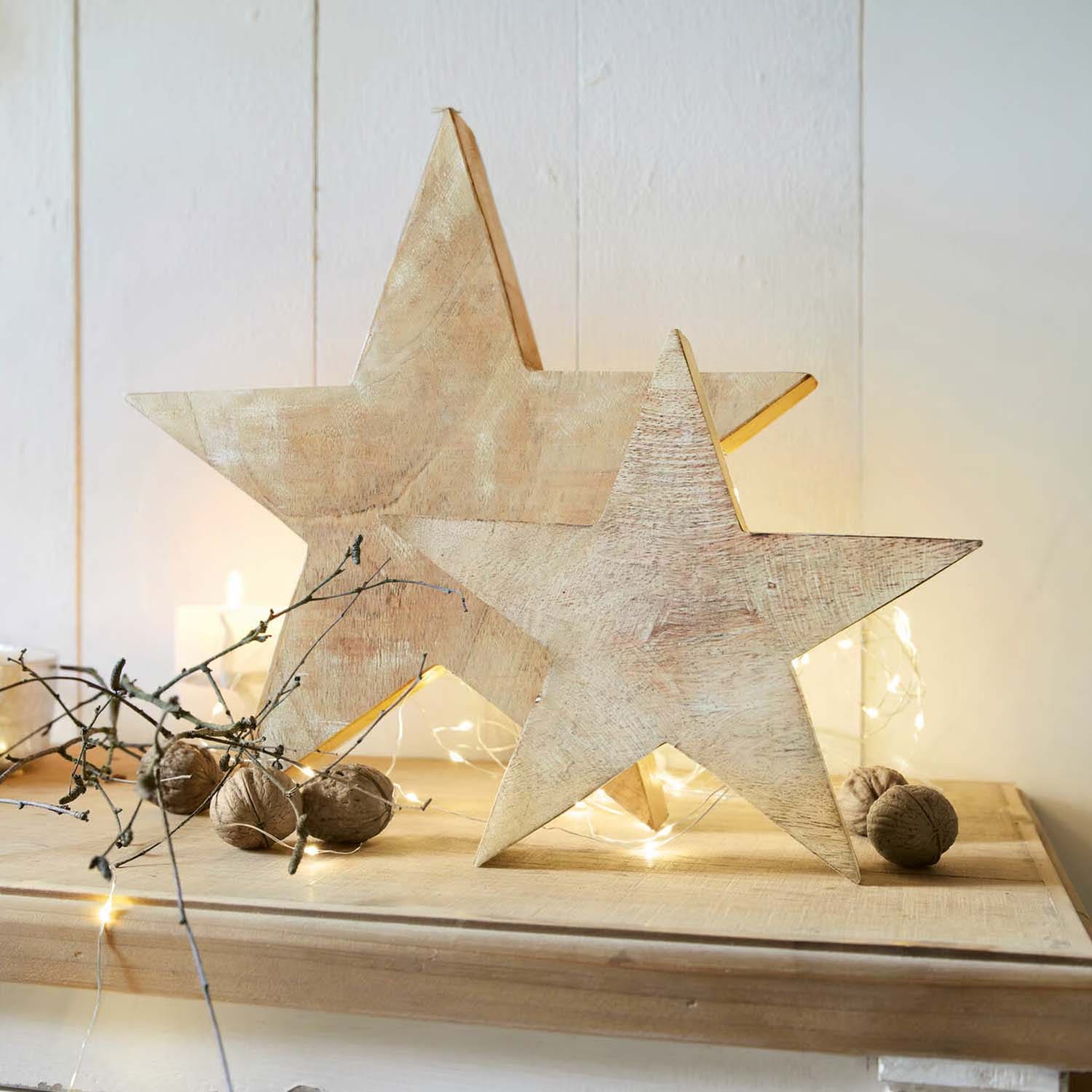 Decorazioni in legno a forma di stelle colore naturale su tavolo con noci e luci LED