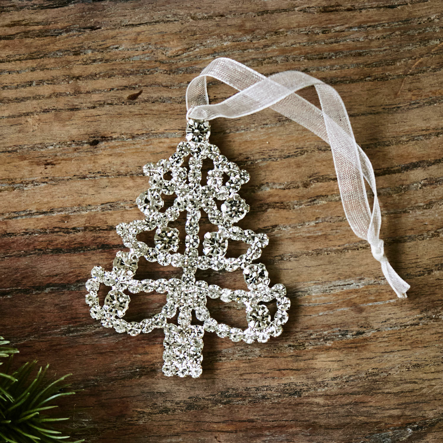 Ciondolo Orilane Decorazione natalizia a forma di albero con cristalli scintillanti e nastro bianco su sfondo in legno
