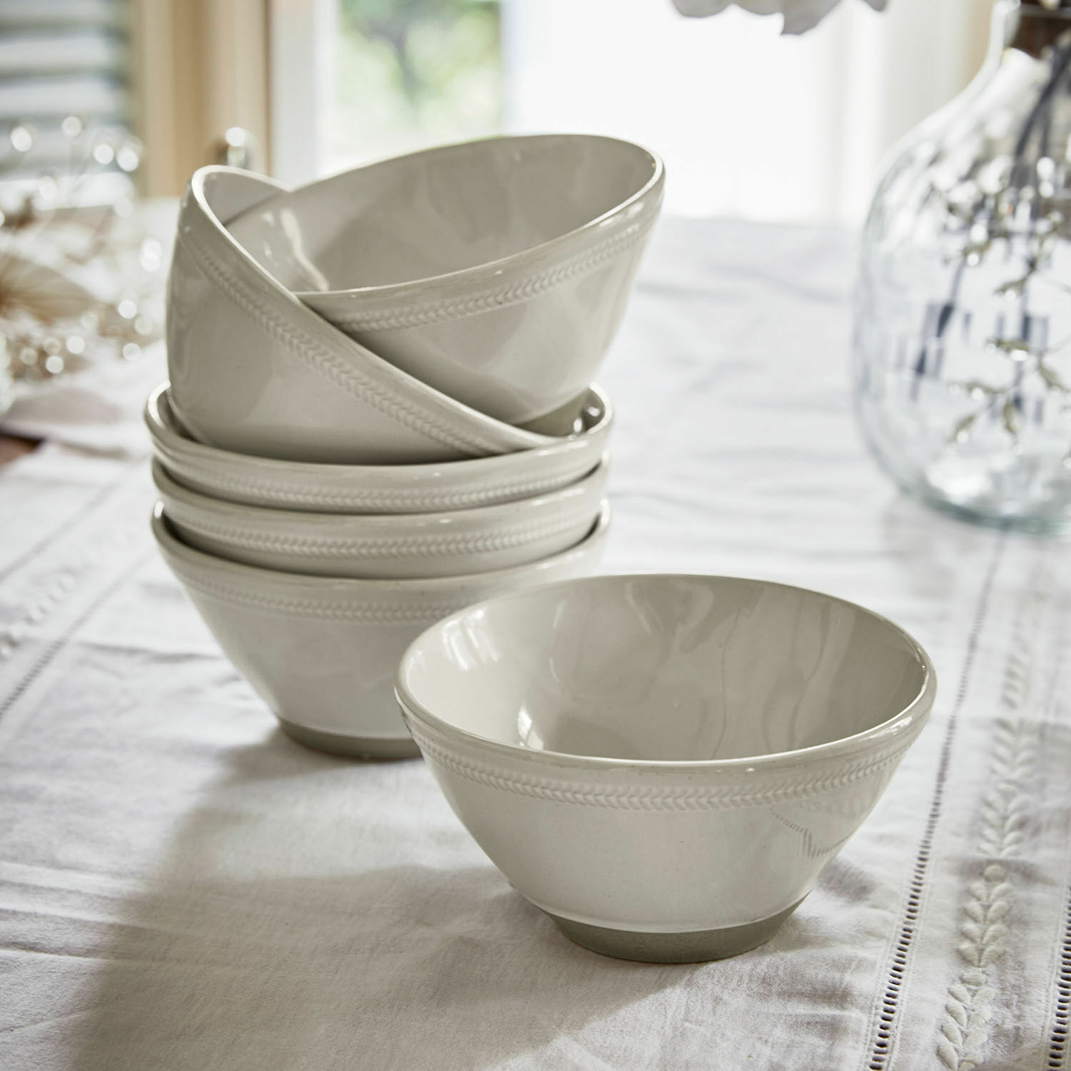 Set di 6 ciotole Norrvik Set di ciotole in ceramica bianca con delicato motivo sul bordo su una tovaglia bianca