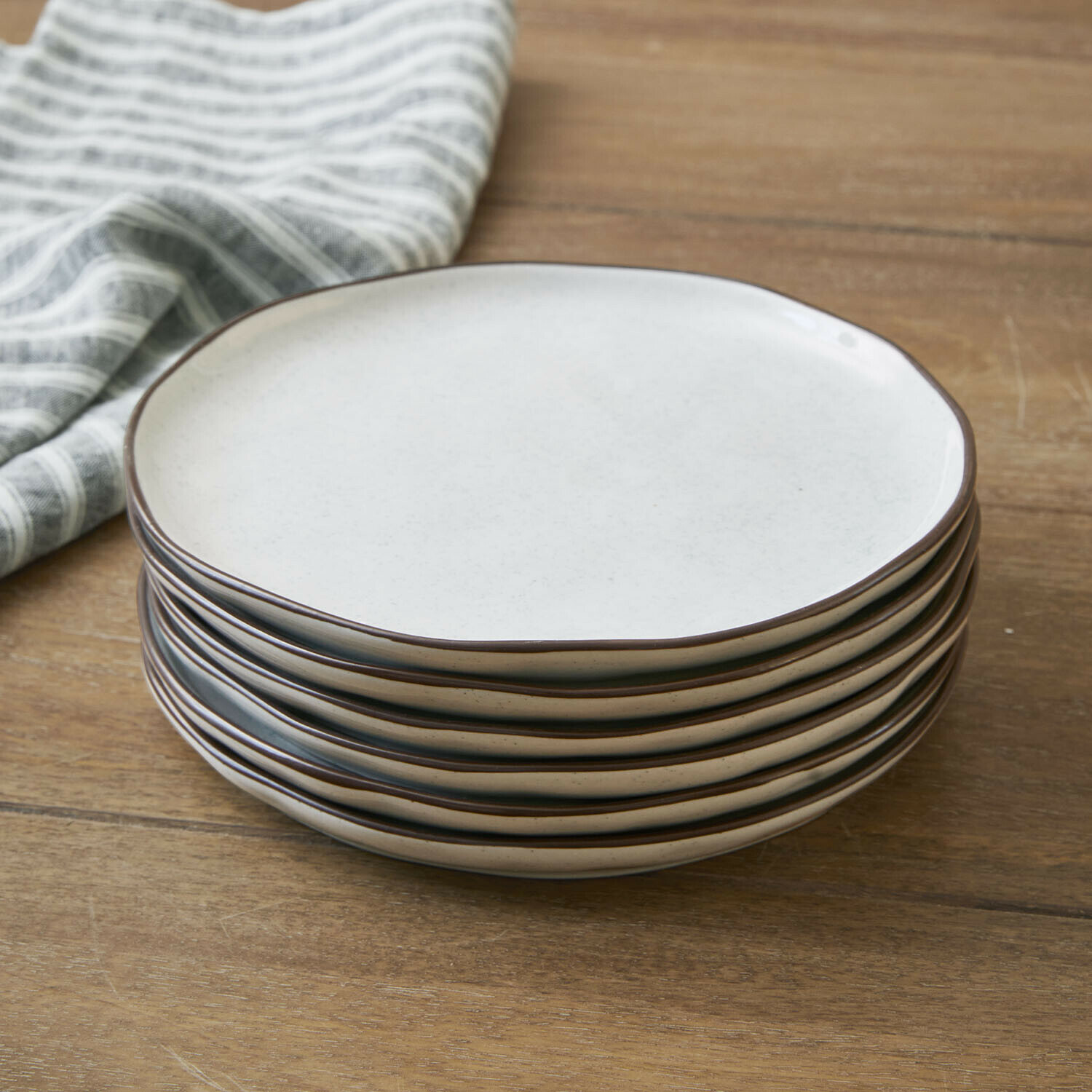 Set di 6 piattini Biarré Set di sei piatti in ceramica color crema con bordo marrone su tavolo in legno