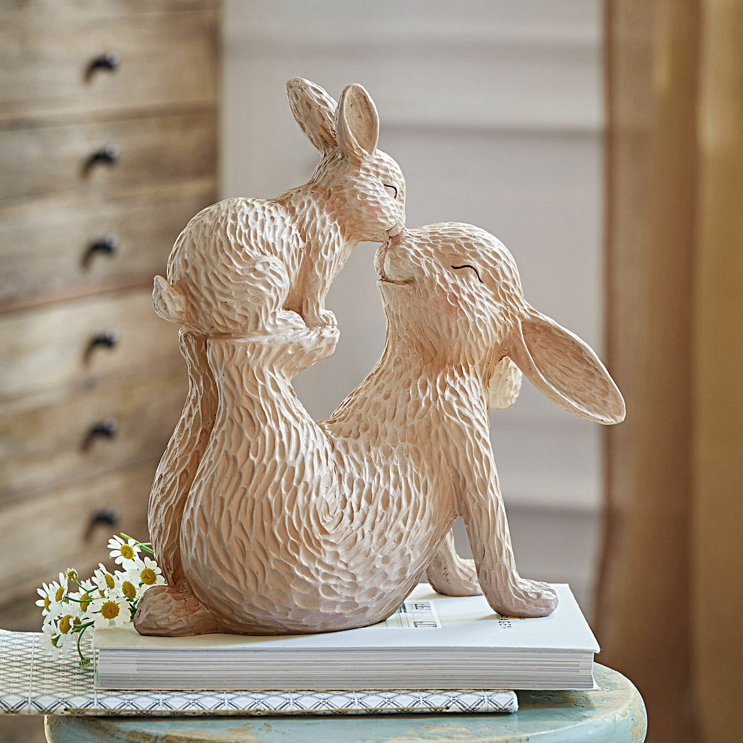 Coniglietto decorativo Trista Figura in ceramica beige di due conigli in posa giocosa su tavolo con libri